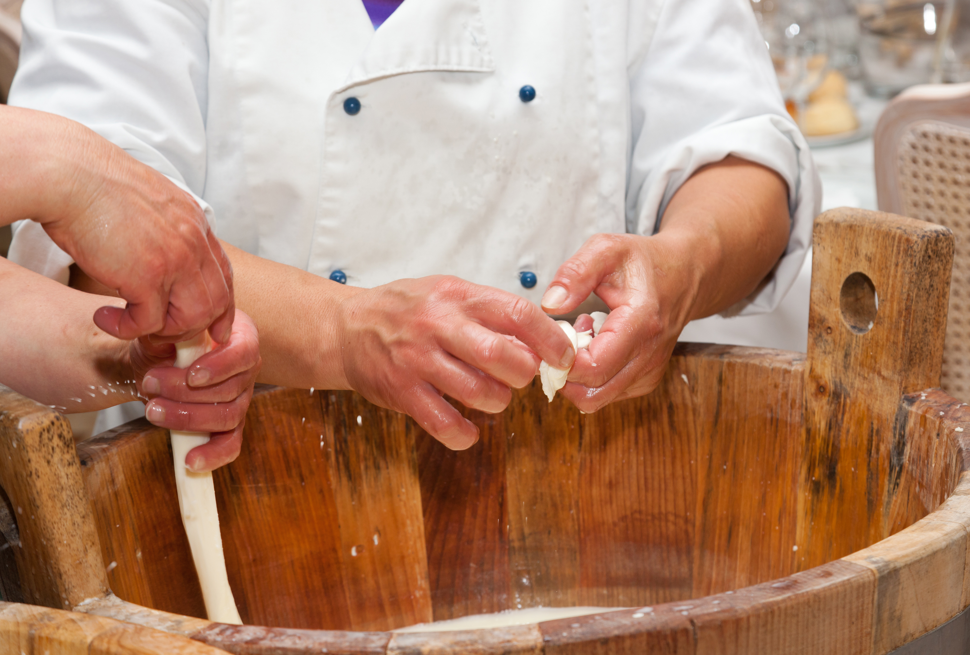 Autentisk håndlavet mozzarella produktion i træbalje med kok i hvid uniform i Campania regionen i Italien