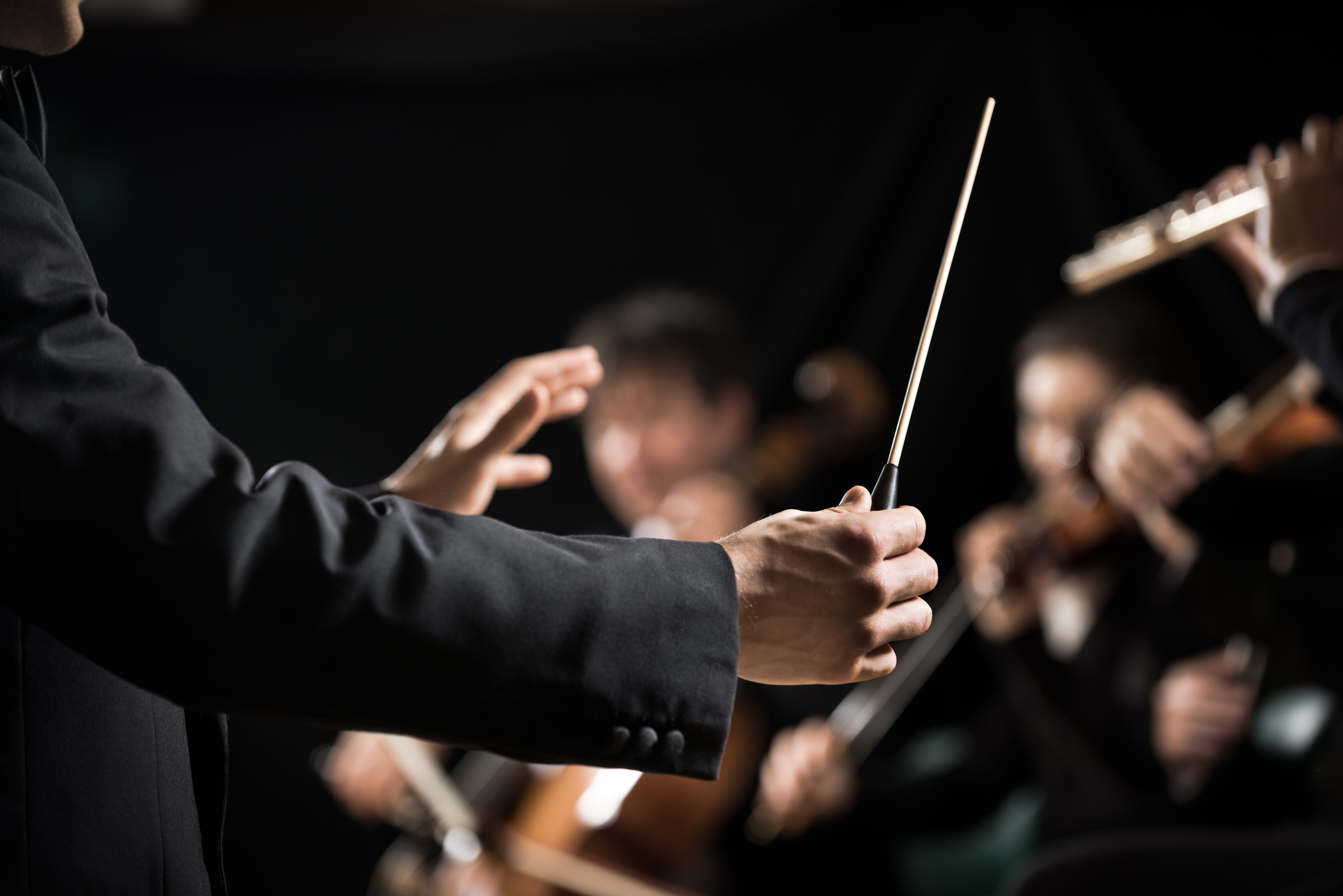 Musikdirigent med taktpind leder orkesterkoncert