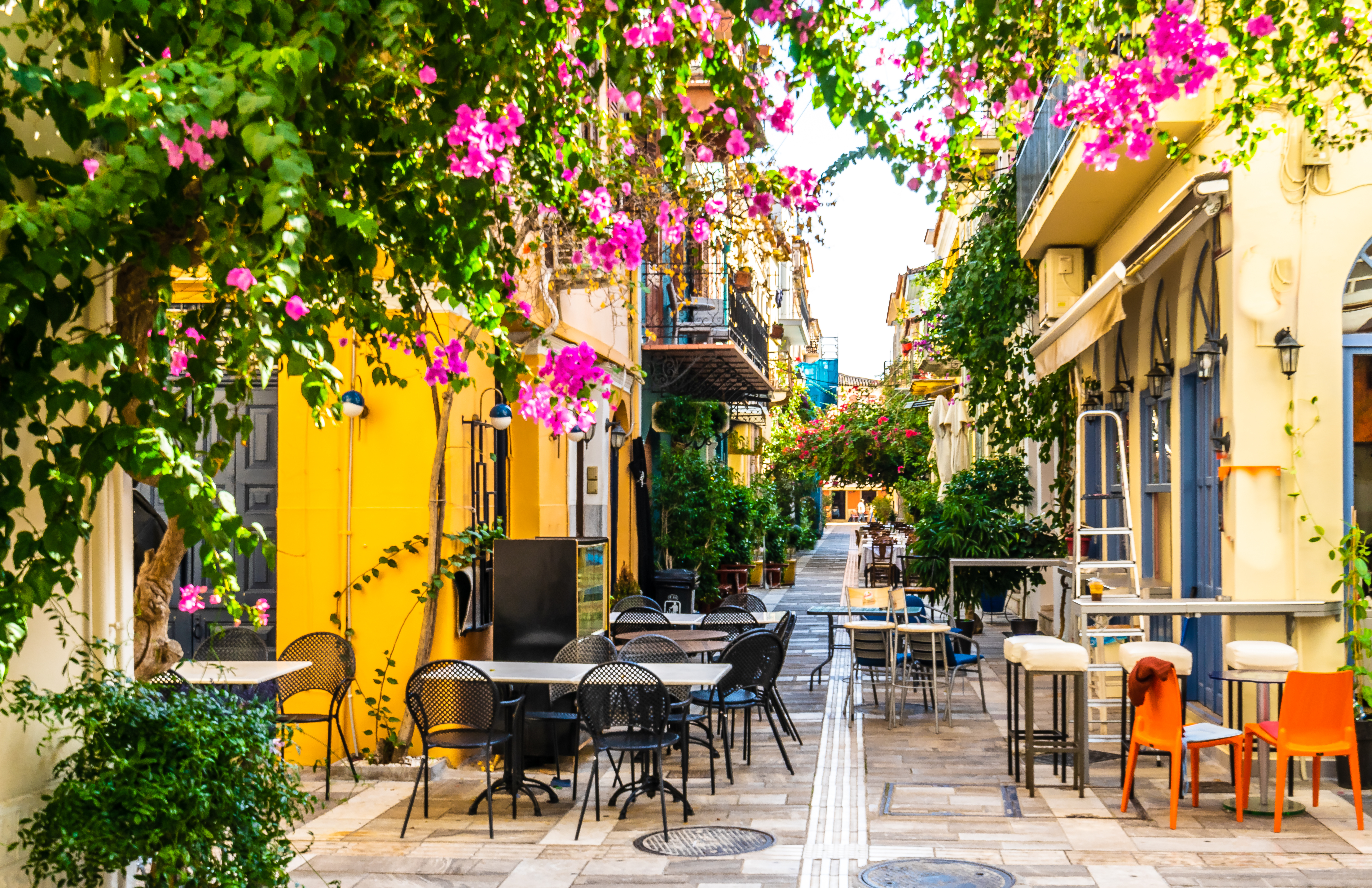 Stemningsfuld gade i den historiske by Nafplio i Grækenland med velbevarede stenhuse, karakteristiske blå skodder og en snæver stengade, der fører op til byens gamle tårn