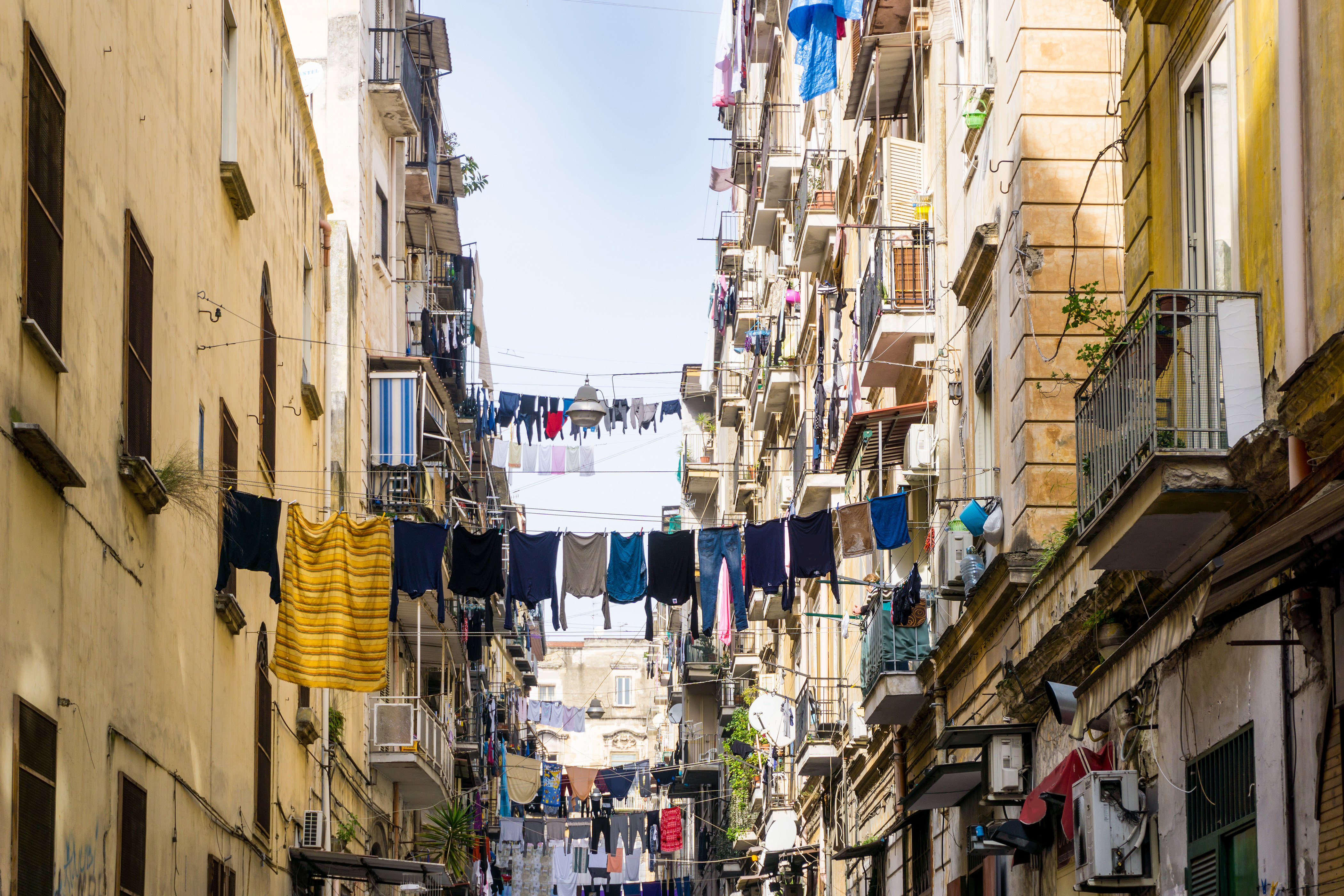 Autentisk gadebillede fra det historiske Napoli med klassiske bygninger og tøj hængt til tørre, der afspejler den ægte italienske livsstil