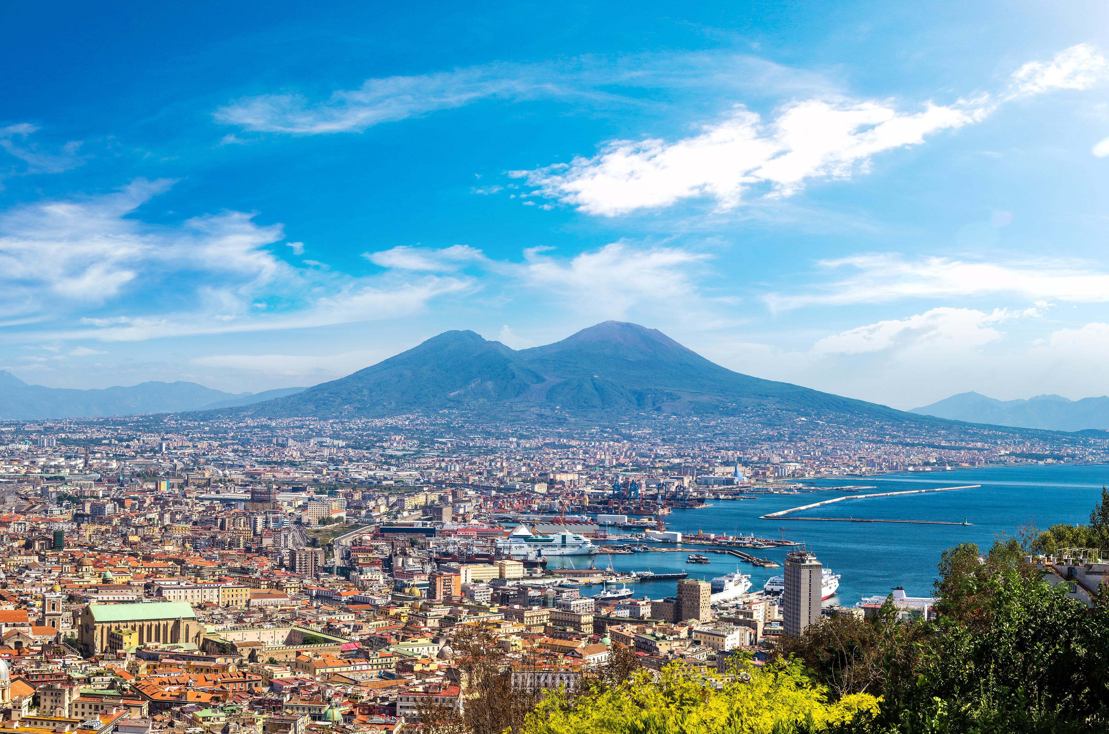 Panorama over Napoli med den historiske Vesuv-vulkan, blåt hav og kystlinje set fra højden på en solrig dag i Campania-regionen