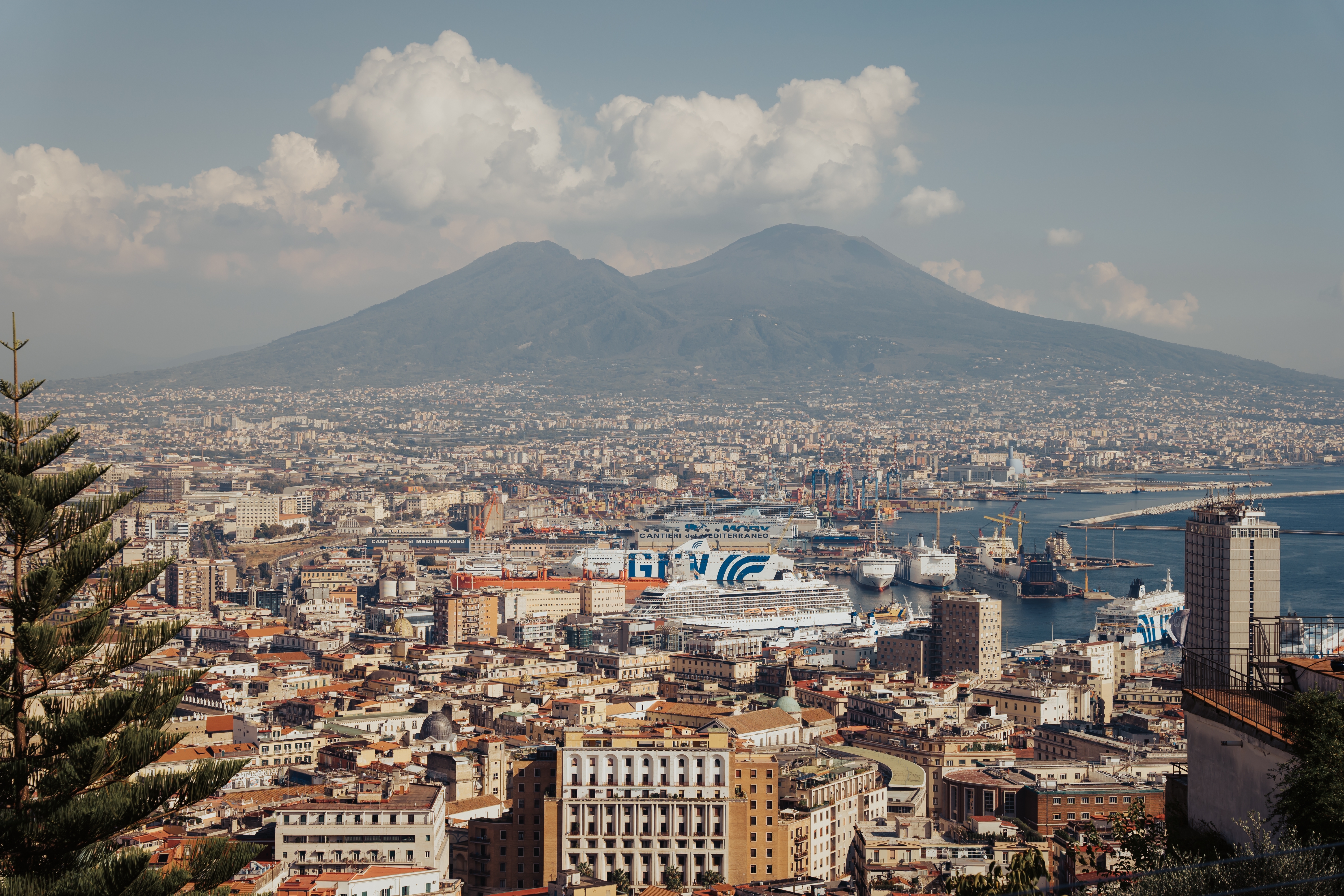 Smukt panorama over Napoli i Syditalien med Vesuv og den travle havn fyldt med krydstogtskibe