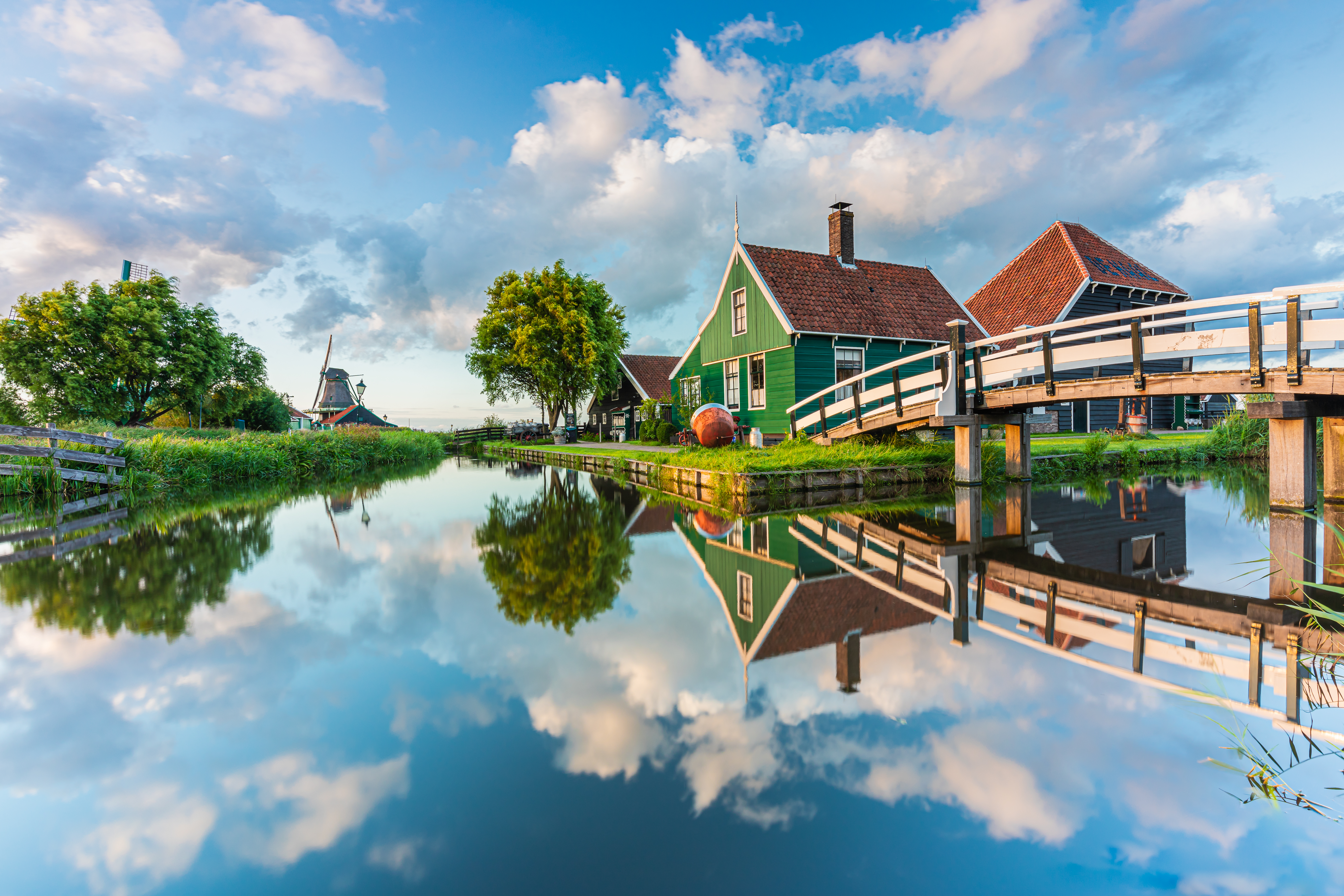 Smuk vandspejling af hollandsk vindmølle og traditionelle træhuse i Zaanse Schans Nederland