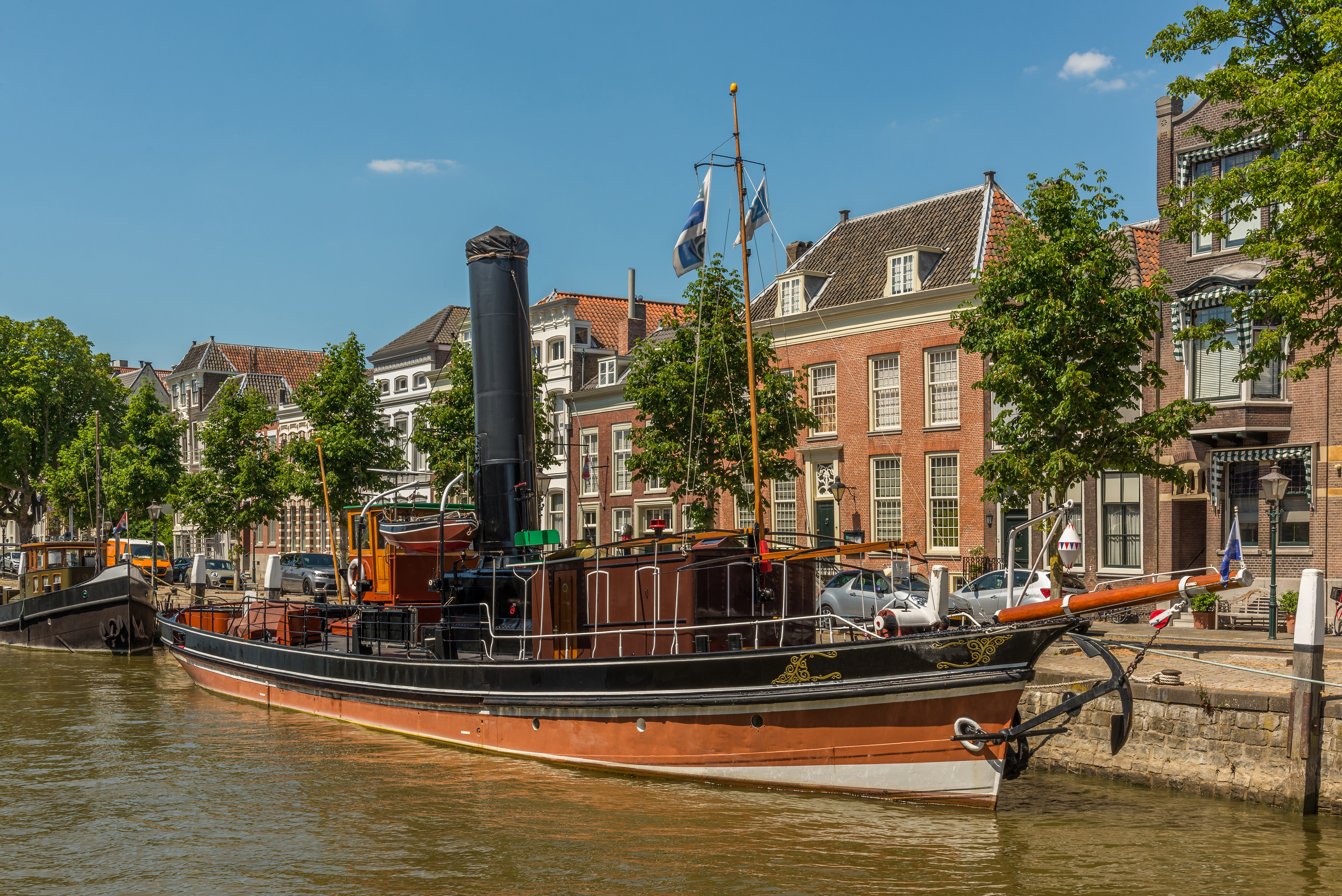 Malerisk dampskib ved kajen i Dordrecht med autentiske hollandske huse og blå himmel