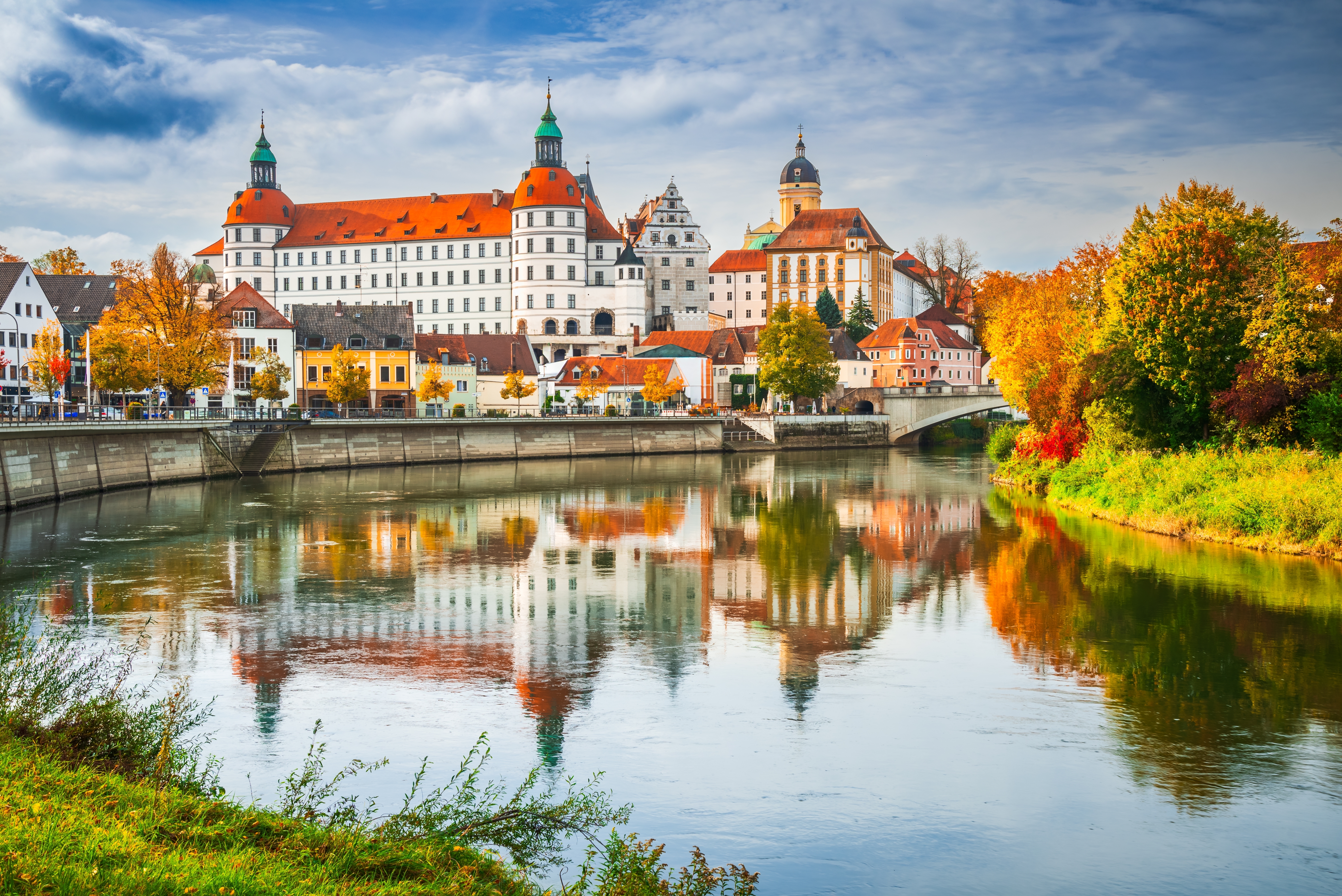 Smuk efterårsudsigt over Neuburg an der Donau med det historiske slot og bykernen reflekteret i Donaufloden omgivet af gyldne træer i Bayern