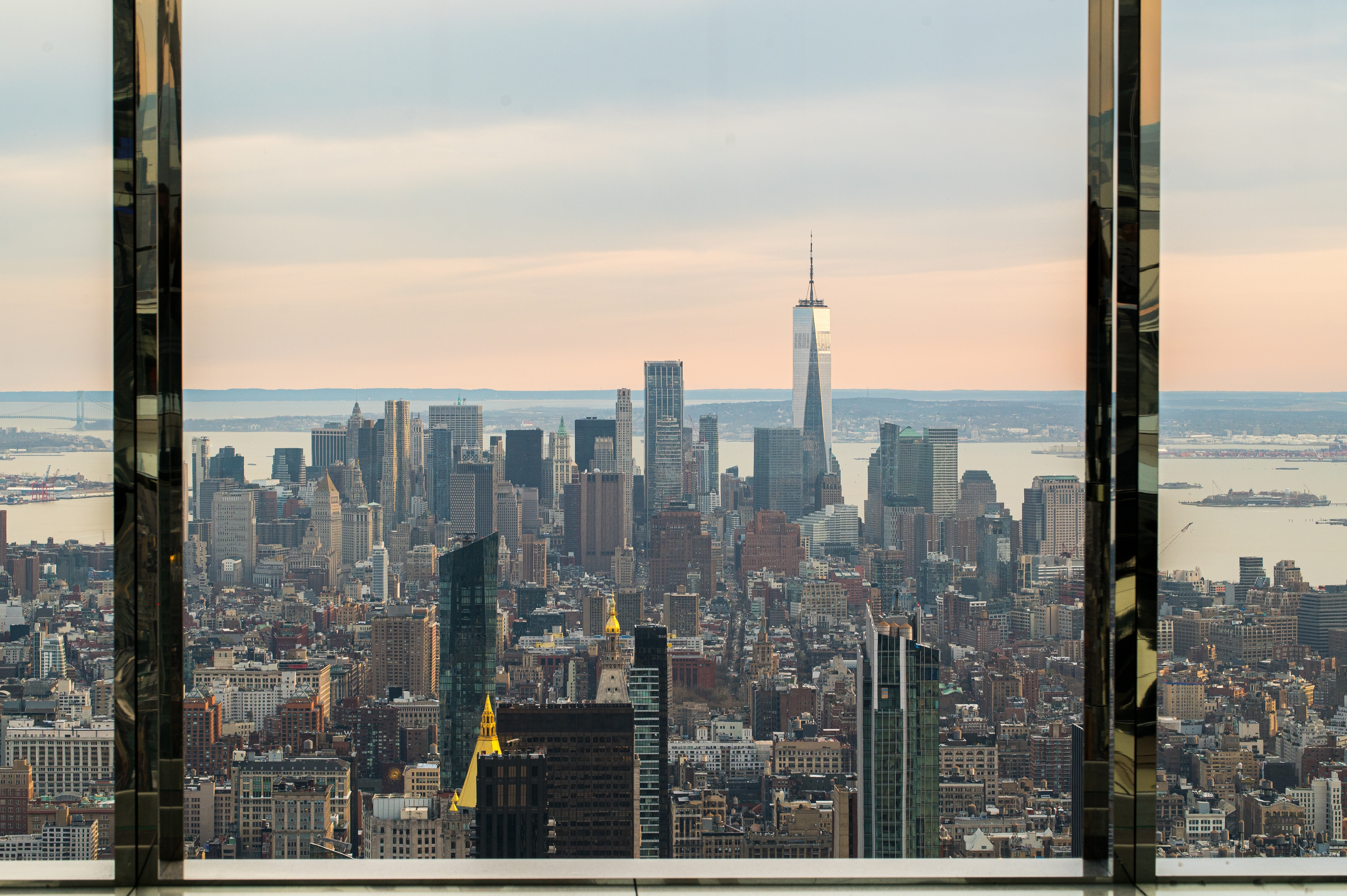 Spektakulær udsigt over Manhattans skyline og One World Trade Center set gennem spejlglasvindue i New York skyskraber
