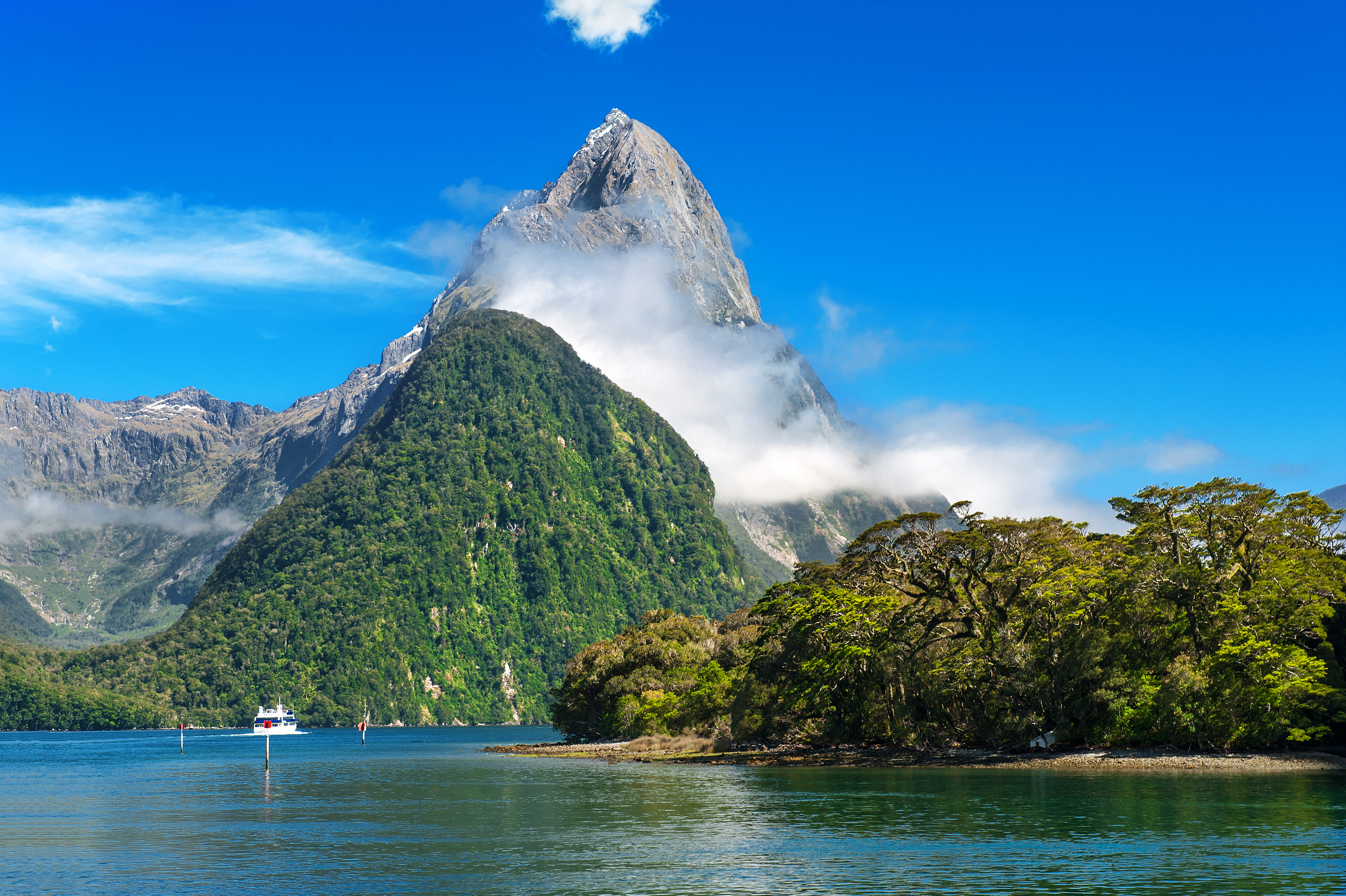 Fantastisk udsigt over bjerg og sø i New Zealand med frodig vegetation og dramatiske skyer