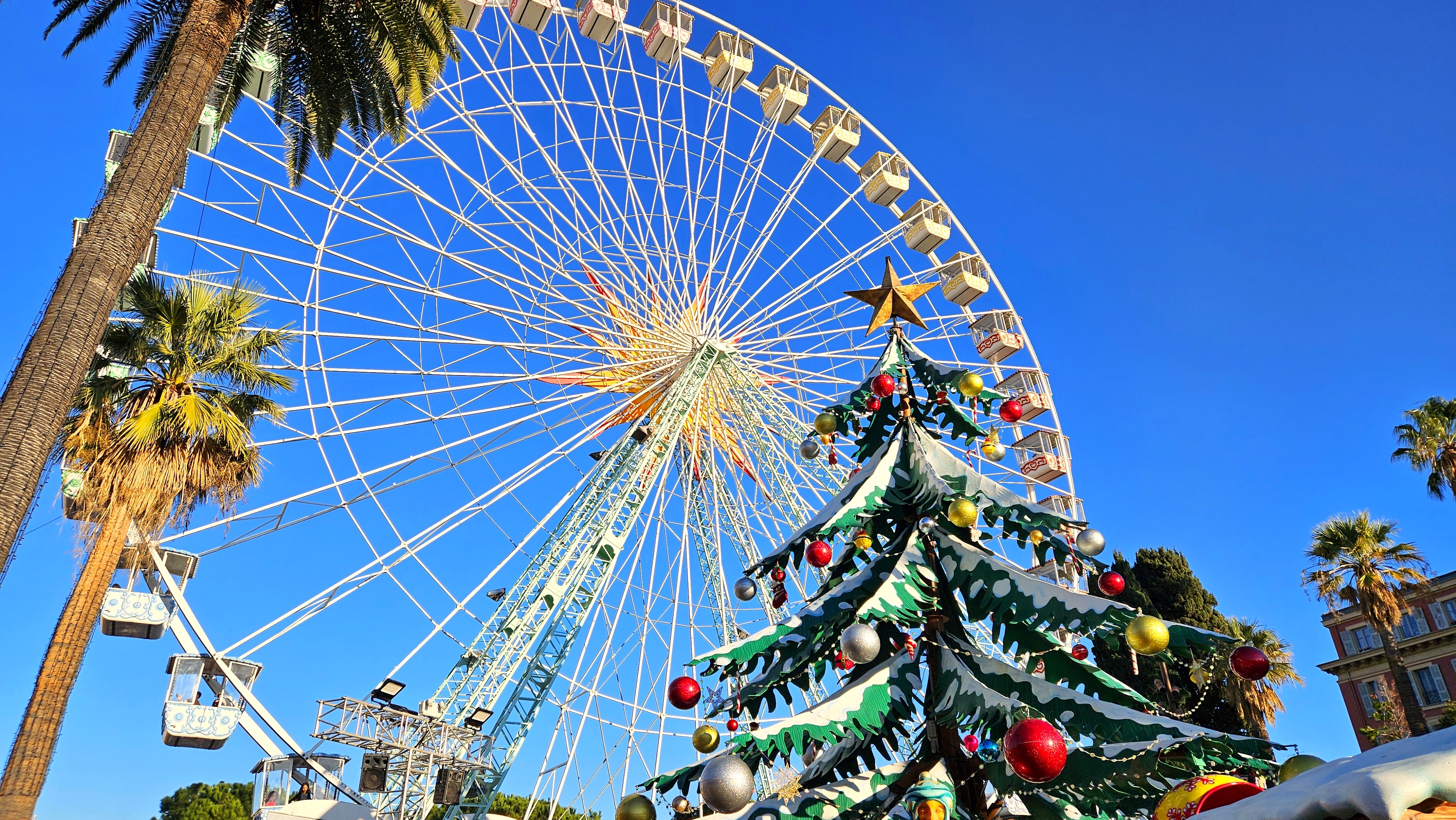 Julestemning i Nice Frankrig med pariserhjul og palmer under blå himmel