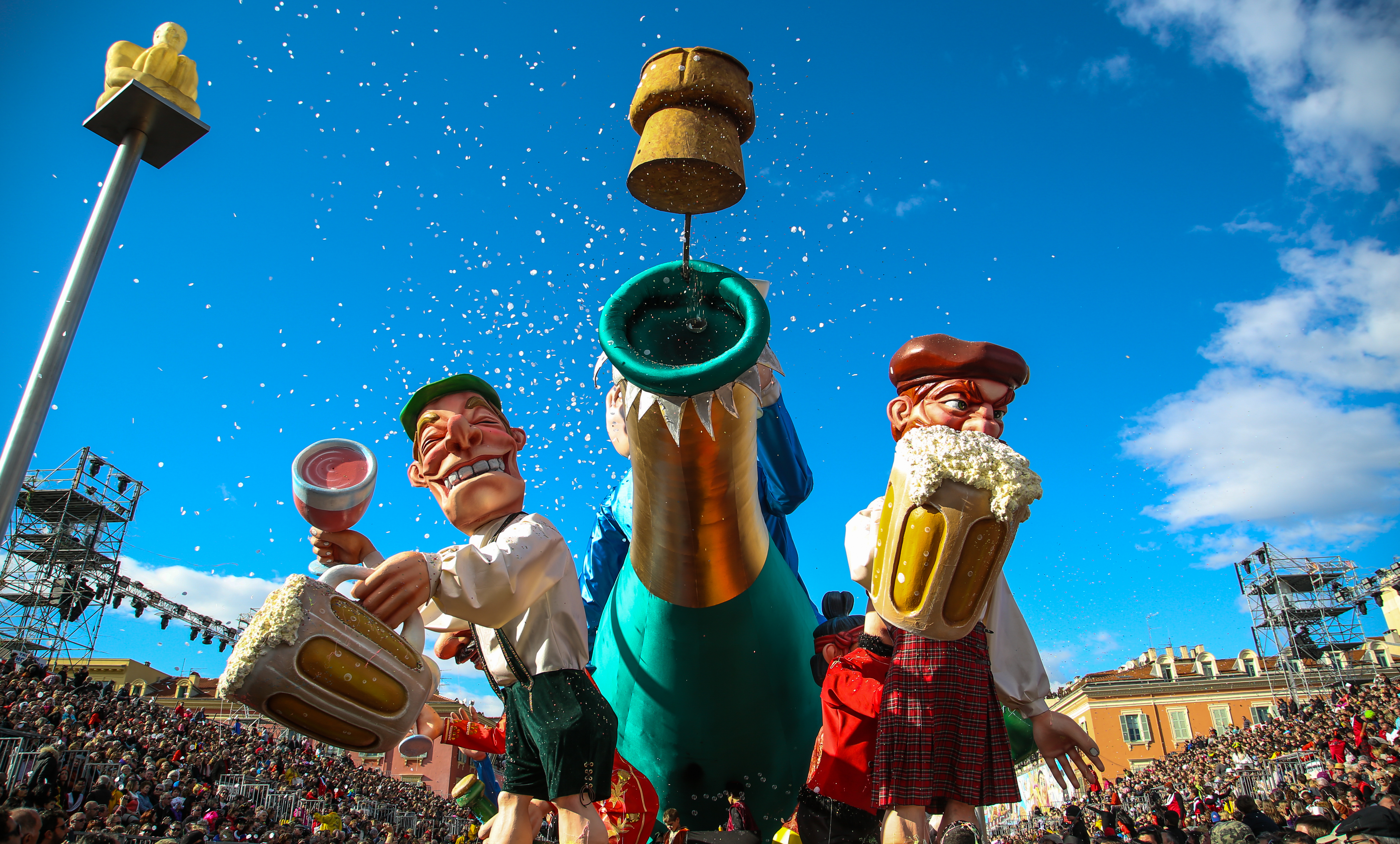 Imponerende karnevalsfigurer med ølkrus og champagne ved Nice Karneval i Sydfrankrig foran store menneskemasser