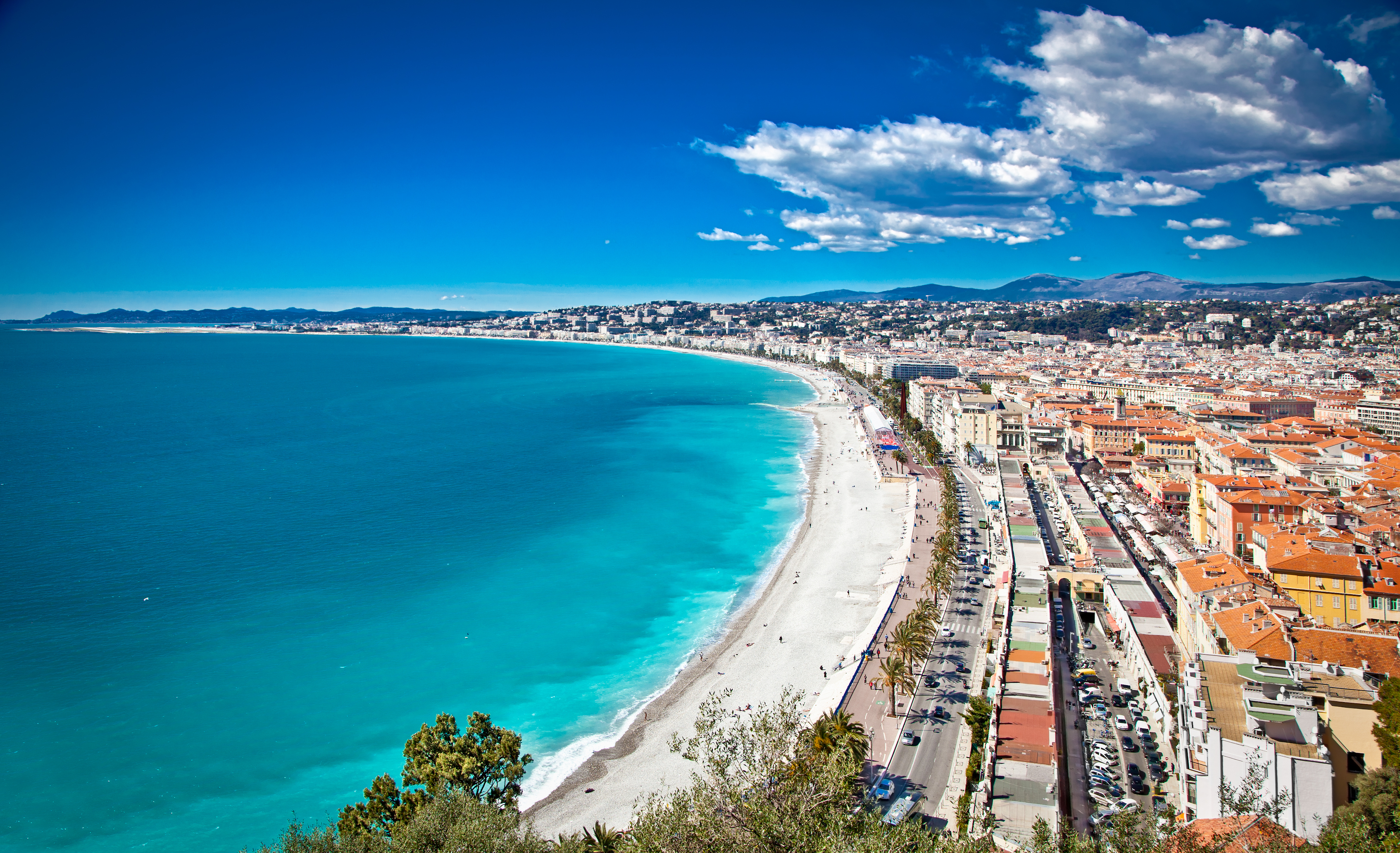 Fuglefoto over den smukke by Nice i Sydfrankrig med Middelhavets turkise vand, den berømte strandpromenade og karakteristiske sydfranske bygninger