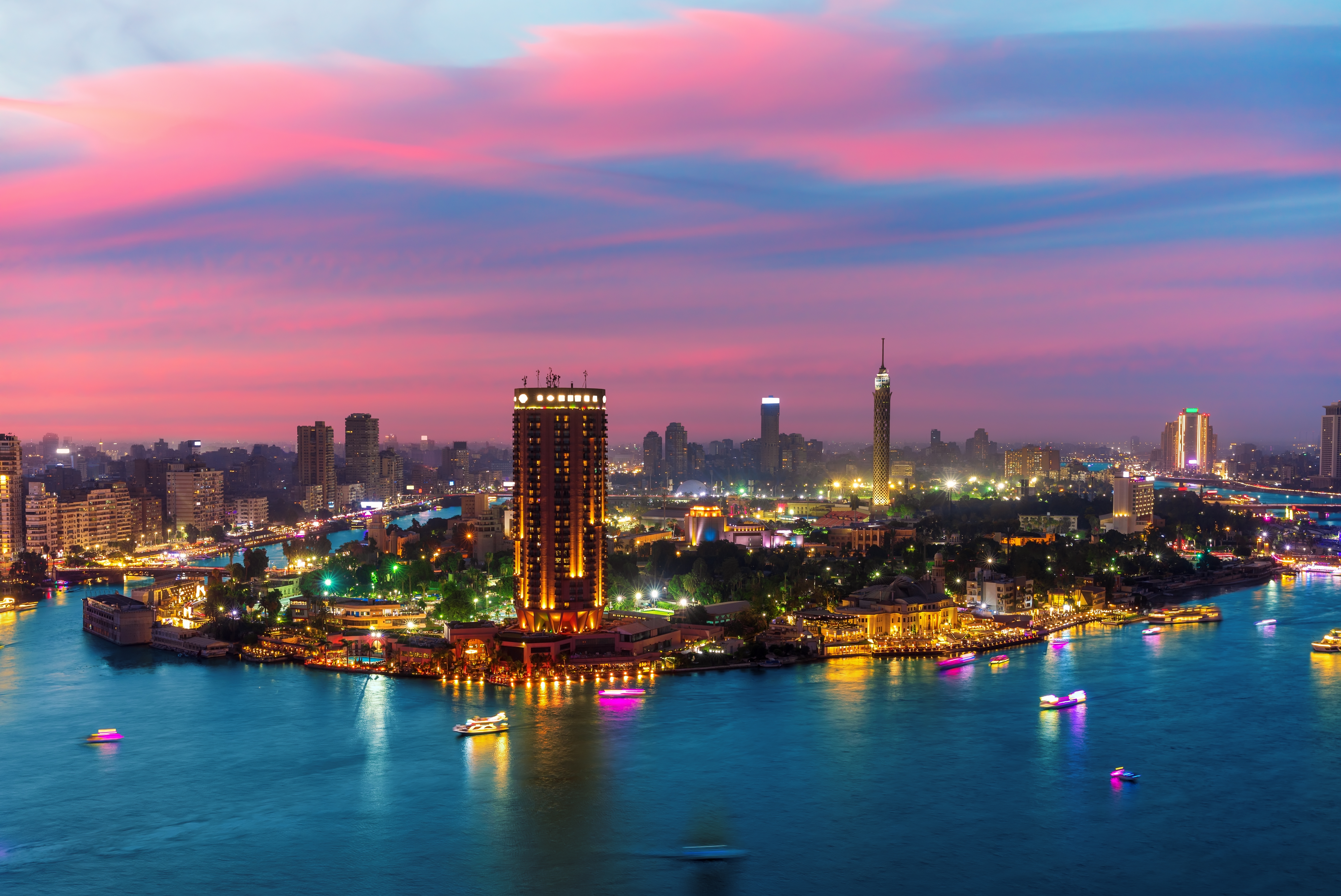 Luftfoto af Nilen ved Kairo med Gezira-øen og byens oplyste skyline ved solnedgang i Egypten