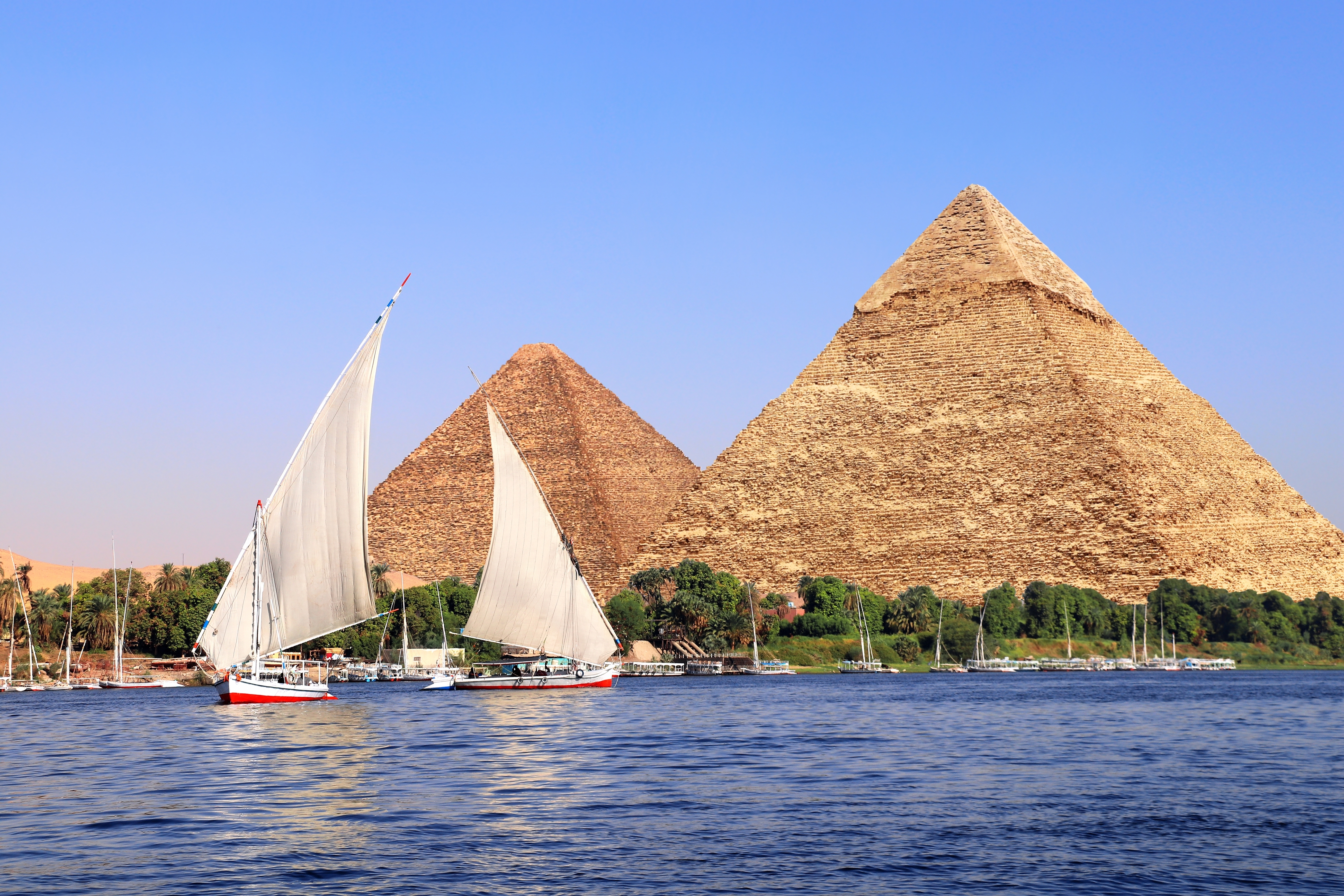 Nilkrydstogt med traditionelle felucca sejlbåde foran de store pyramider ved Giza i Egypten