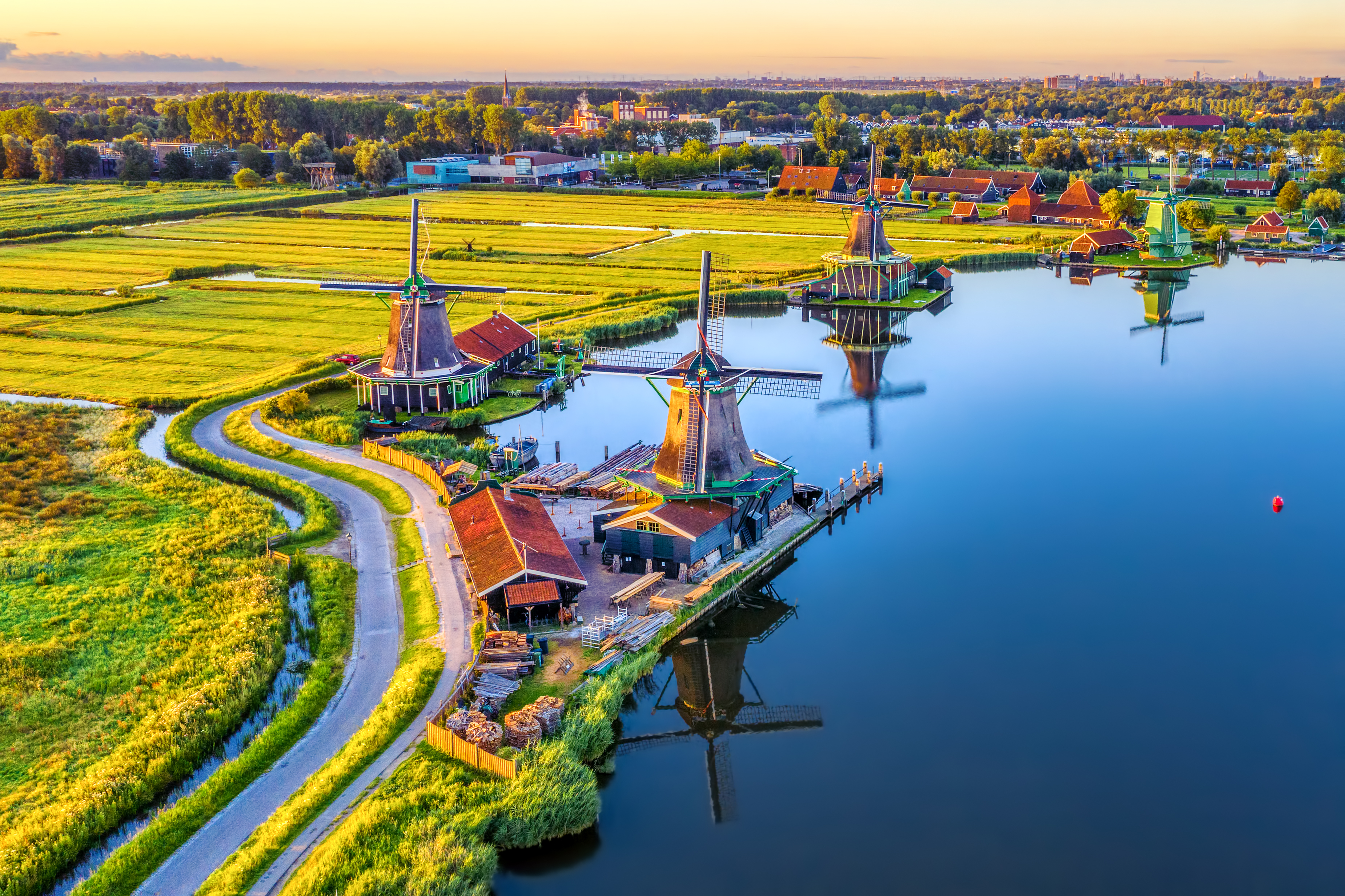 Charmerende luftperspektiv af de ikoniske vindmøller i Zaanse Schans omgivet af frodige marker og kanaler i det smukke nordhollandske landskab ved daggry