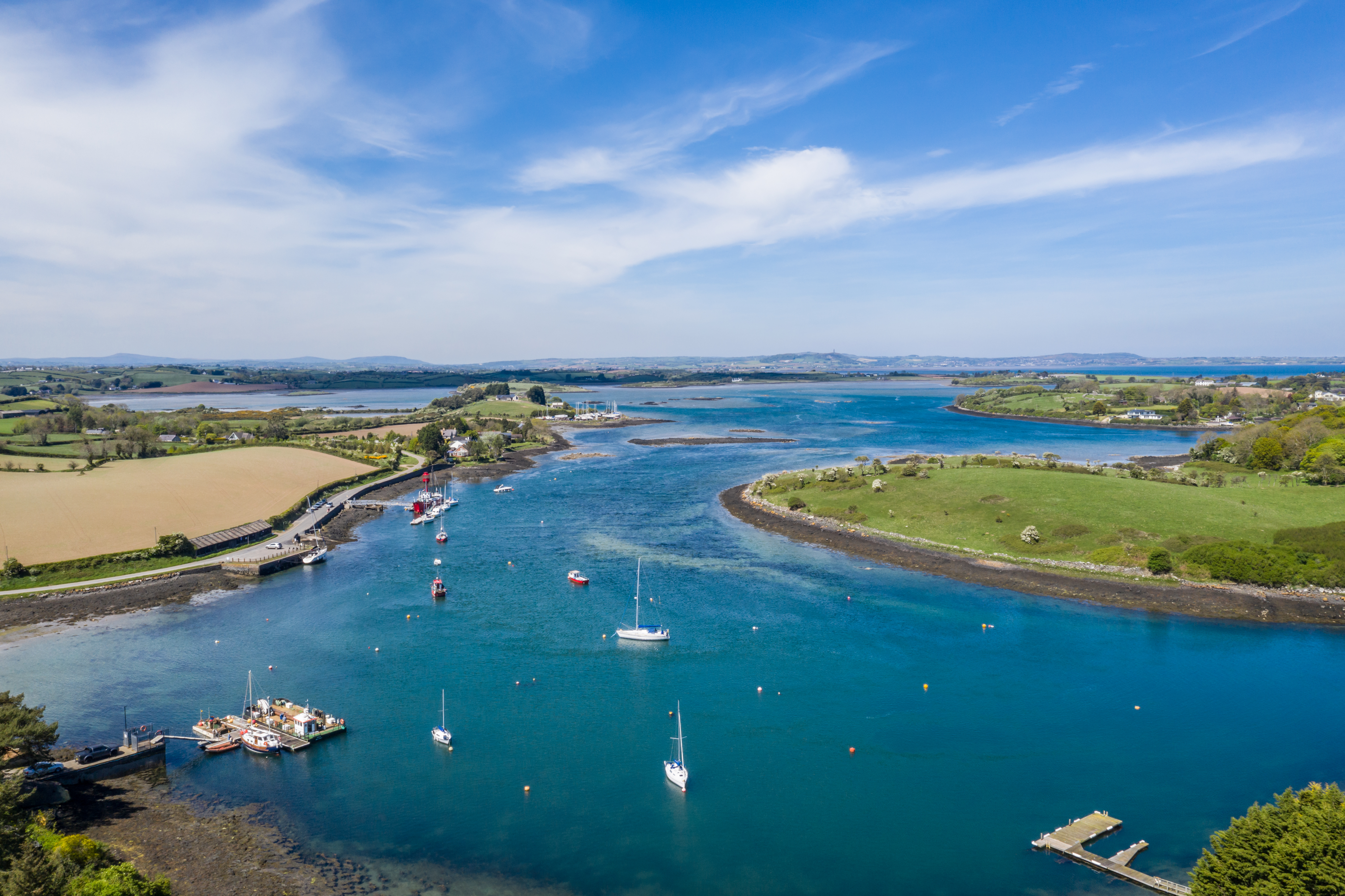 Imponerende fugleperspektiv over Strangford Lough ved Sketrick i Nordirland med hvide sejlbåde på det blå vand og grønne marker en sommerdag