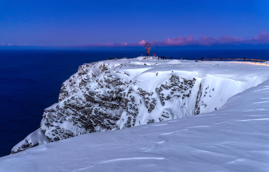 Nordkap Europas nordligste punkt med sne og turister i blå aftenlys Norge