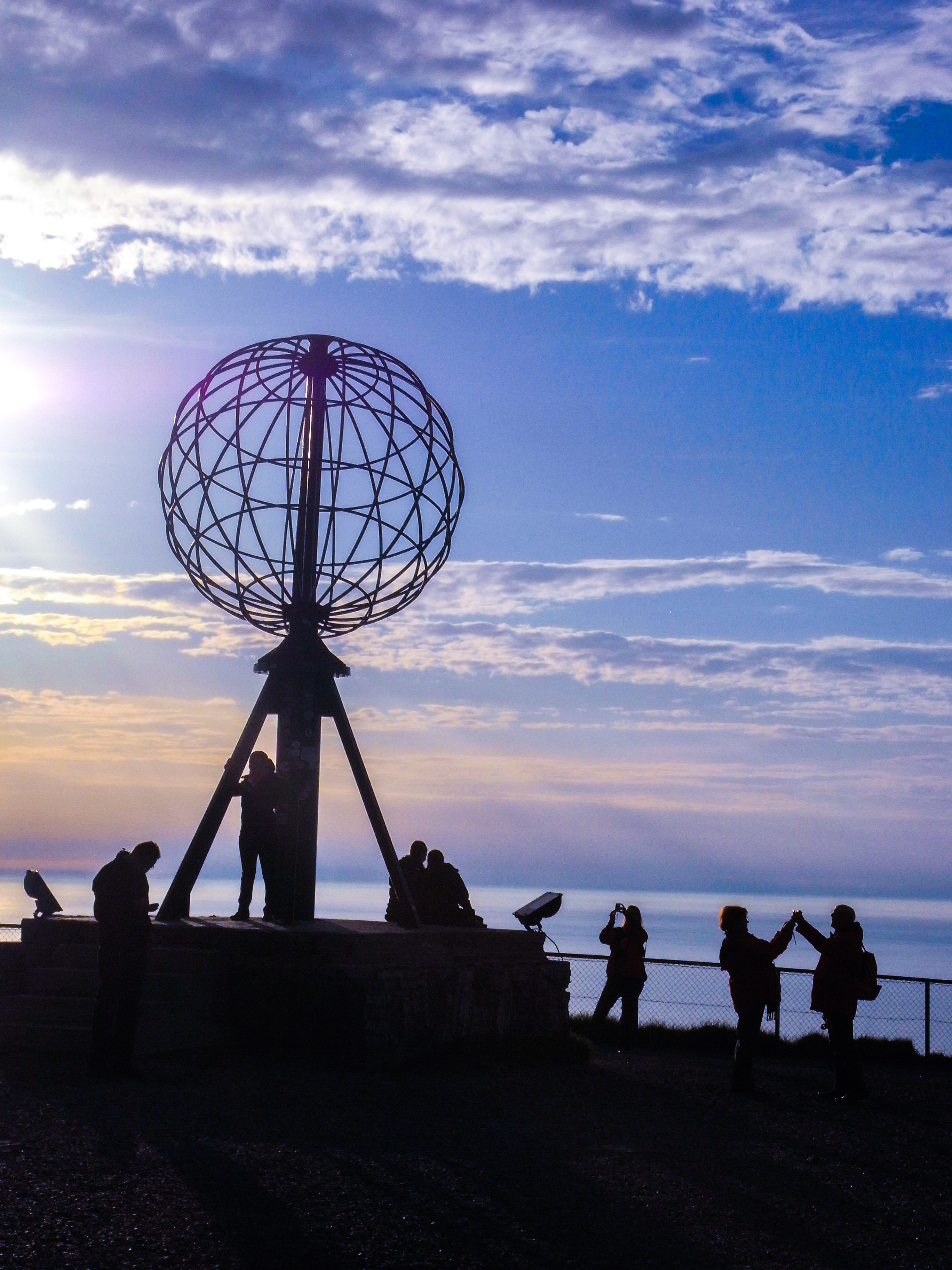 Turister ved Nordkap monumentet i det arktiske Norge under dramatisk himmel