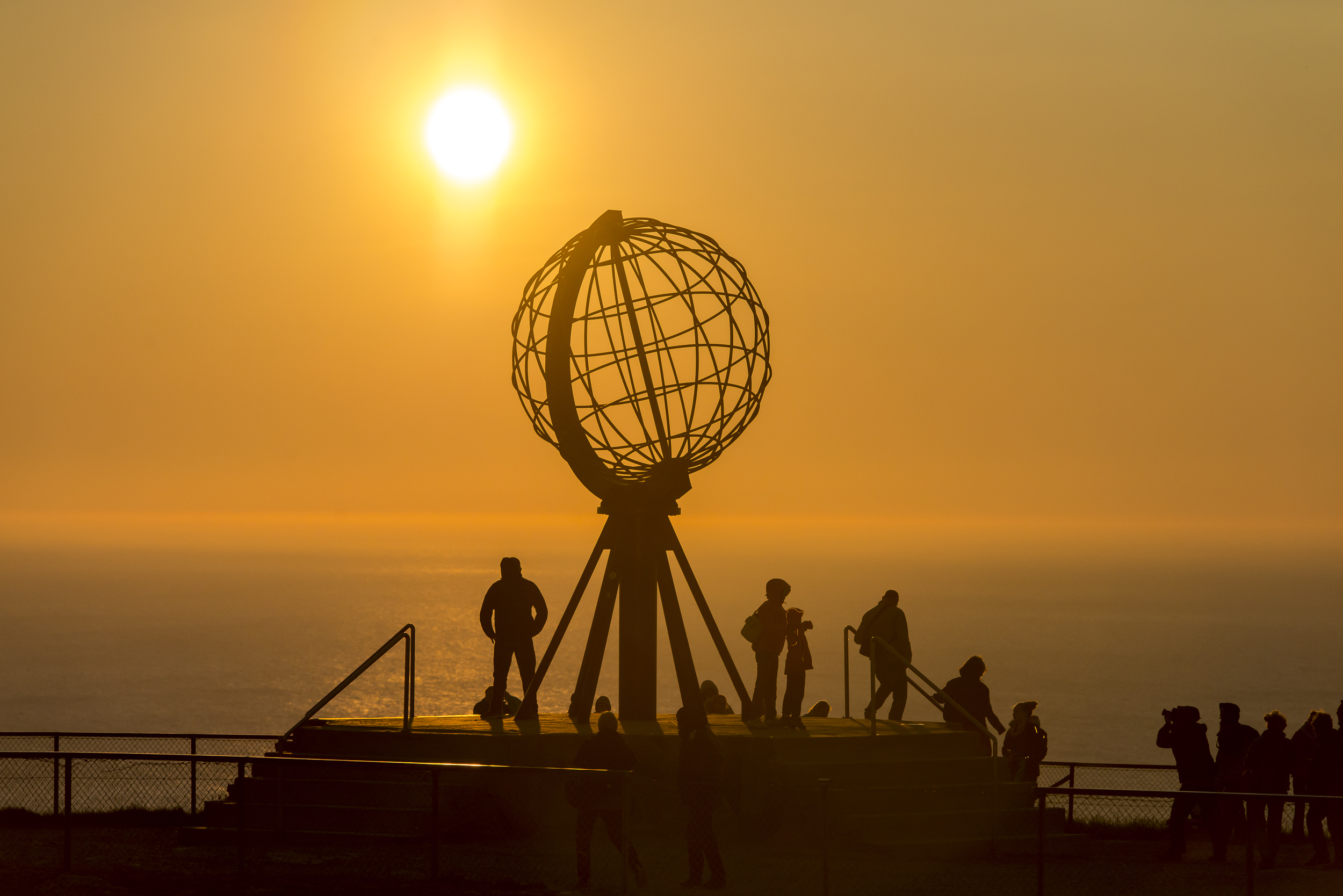 Nordkap monument i Norge med turister under den gylden midnatssol