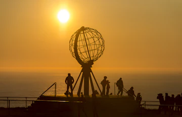 Nordkap monument i Norge med turister under den gylden midnatssol