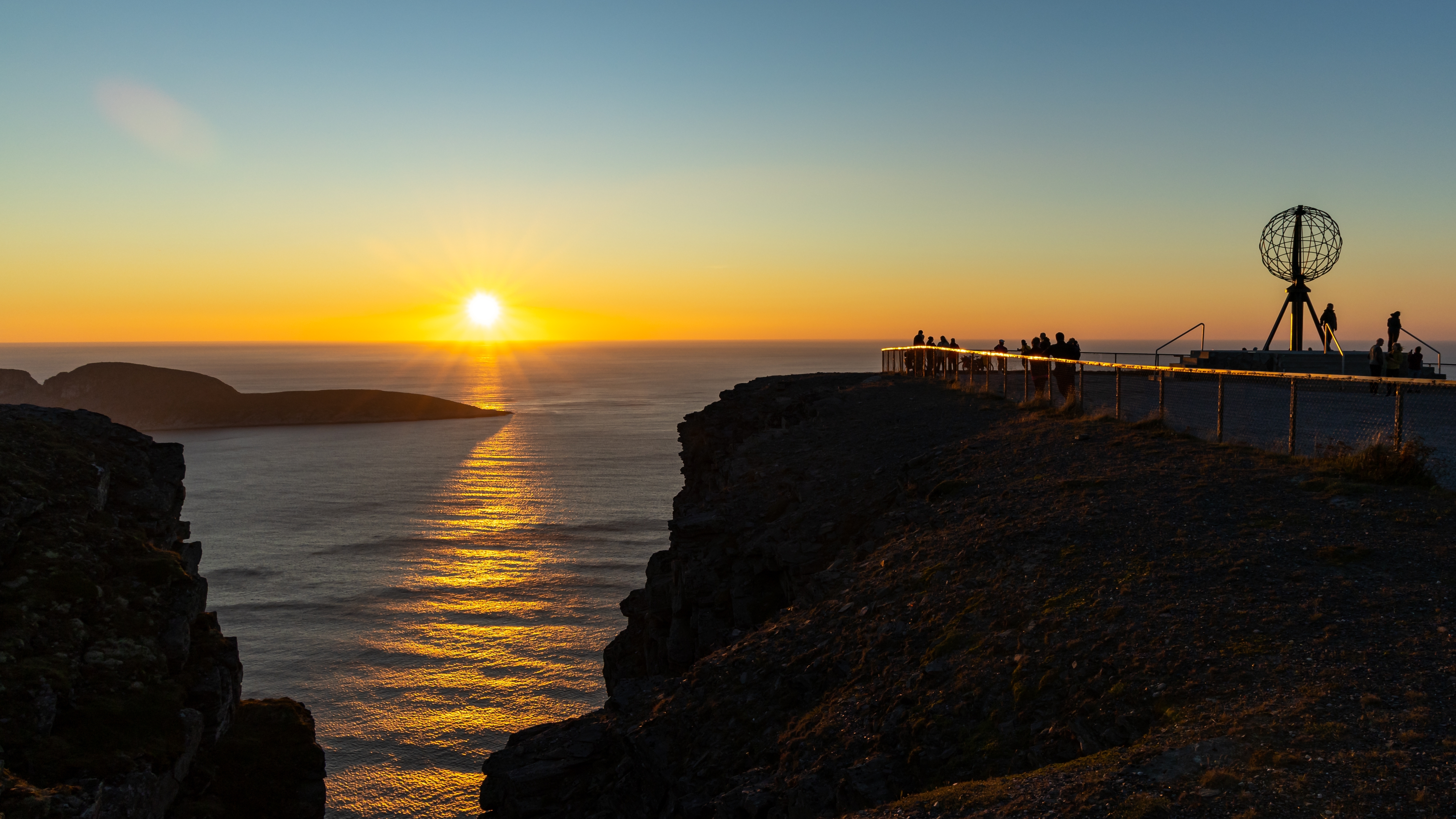 Det berømte globus-monument på Nordkapp i Norge silhuetteret mod den smukke solnedgang over Ishavet, der skaber en magisk stemning på klippen