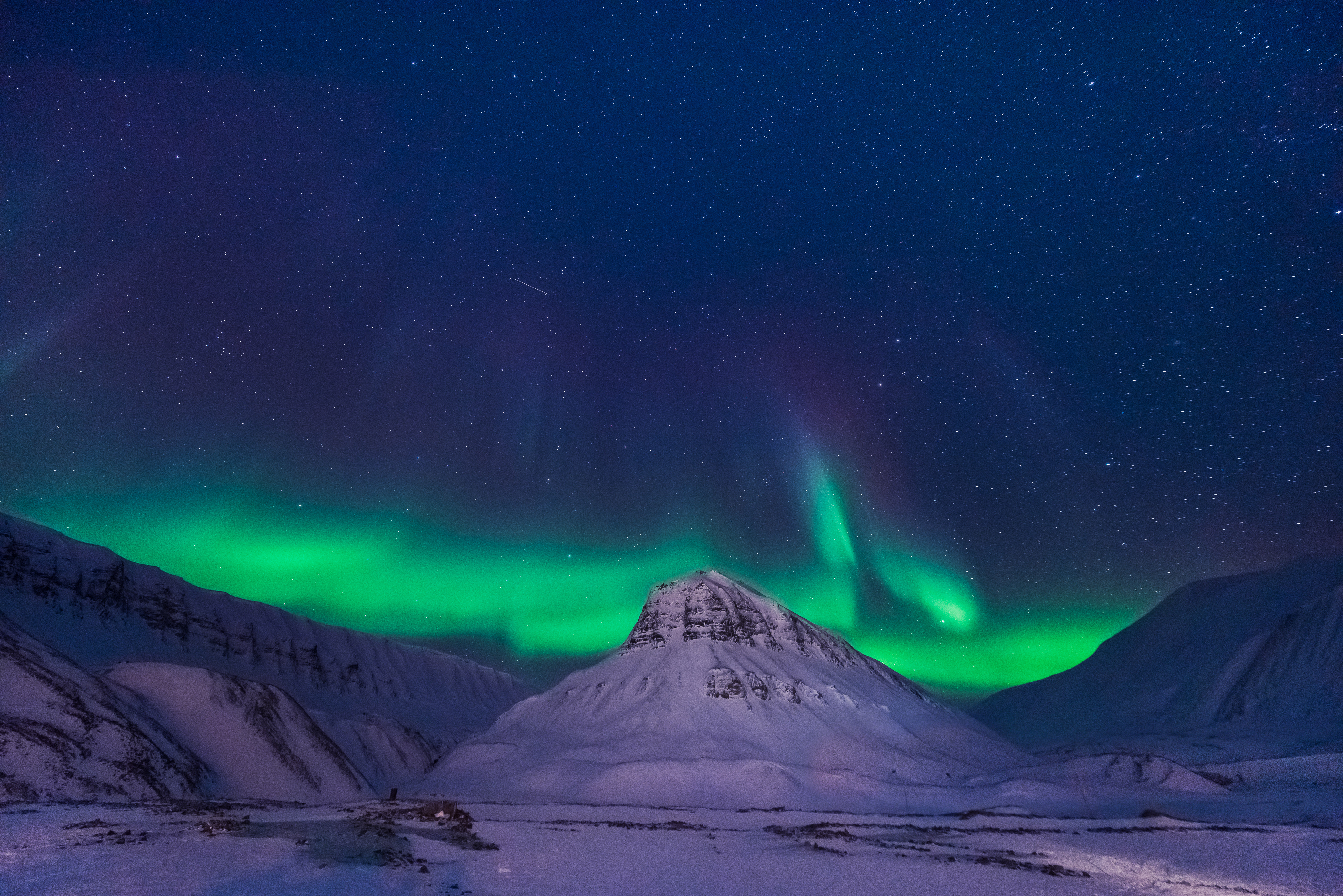 Magisk nordlys over islandsk bjerglandskab med sne under stjernehimlen