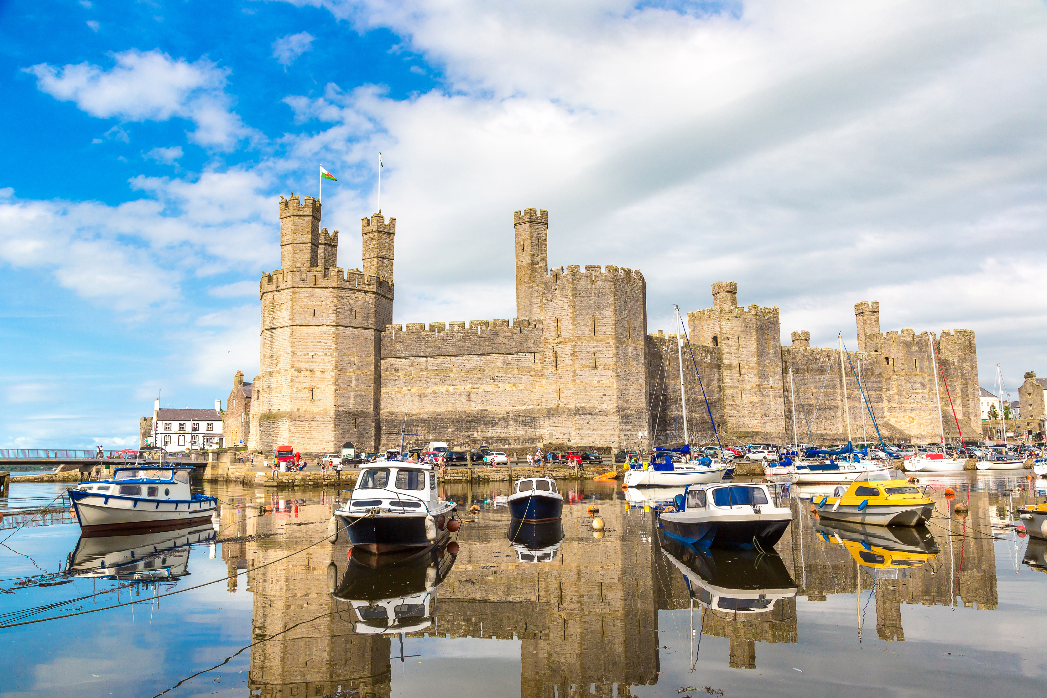 Det historiske Caernarfon Slot med baade fortoejet i den fredelige havn i Wales