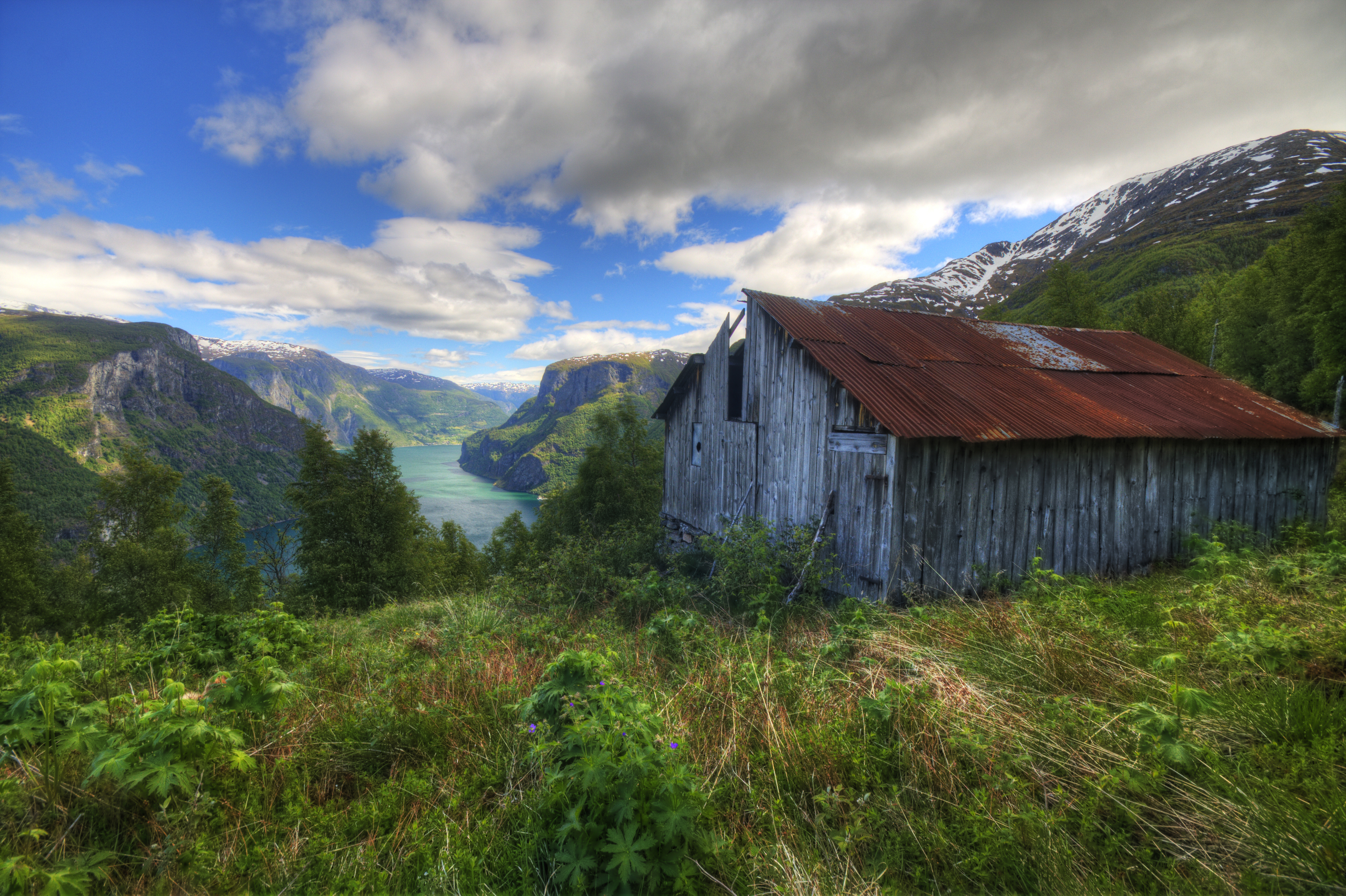 Norsk sommerfjældlandskab med traditionel træbygning og fjordudsigt