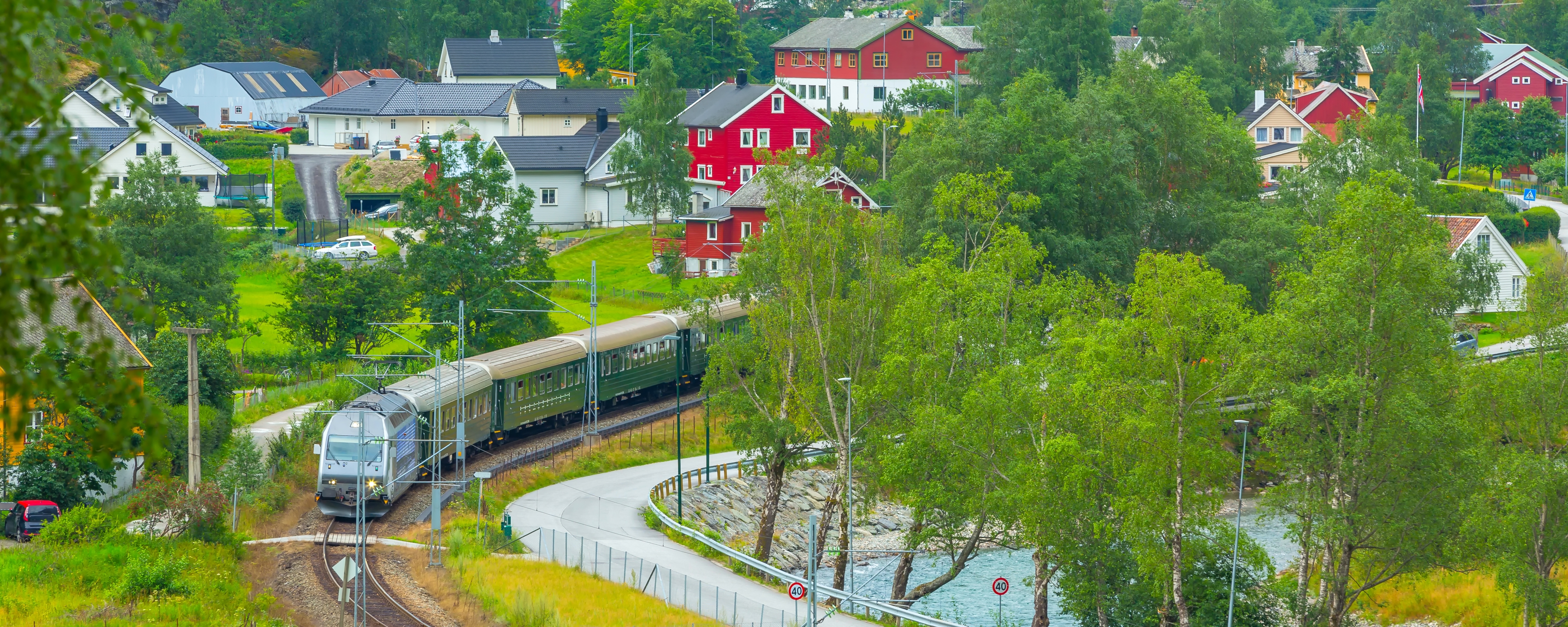 Oplev Flamsbana-toget på rejse gennem den naturskønne Flåm-dal med traditionelle norske huse og Sognefjorden i baggrunden