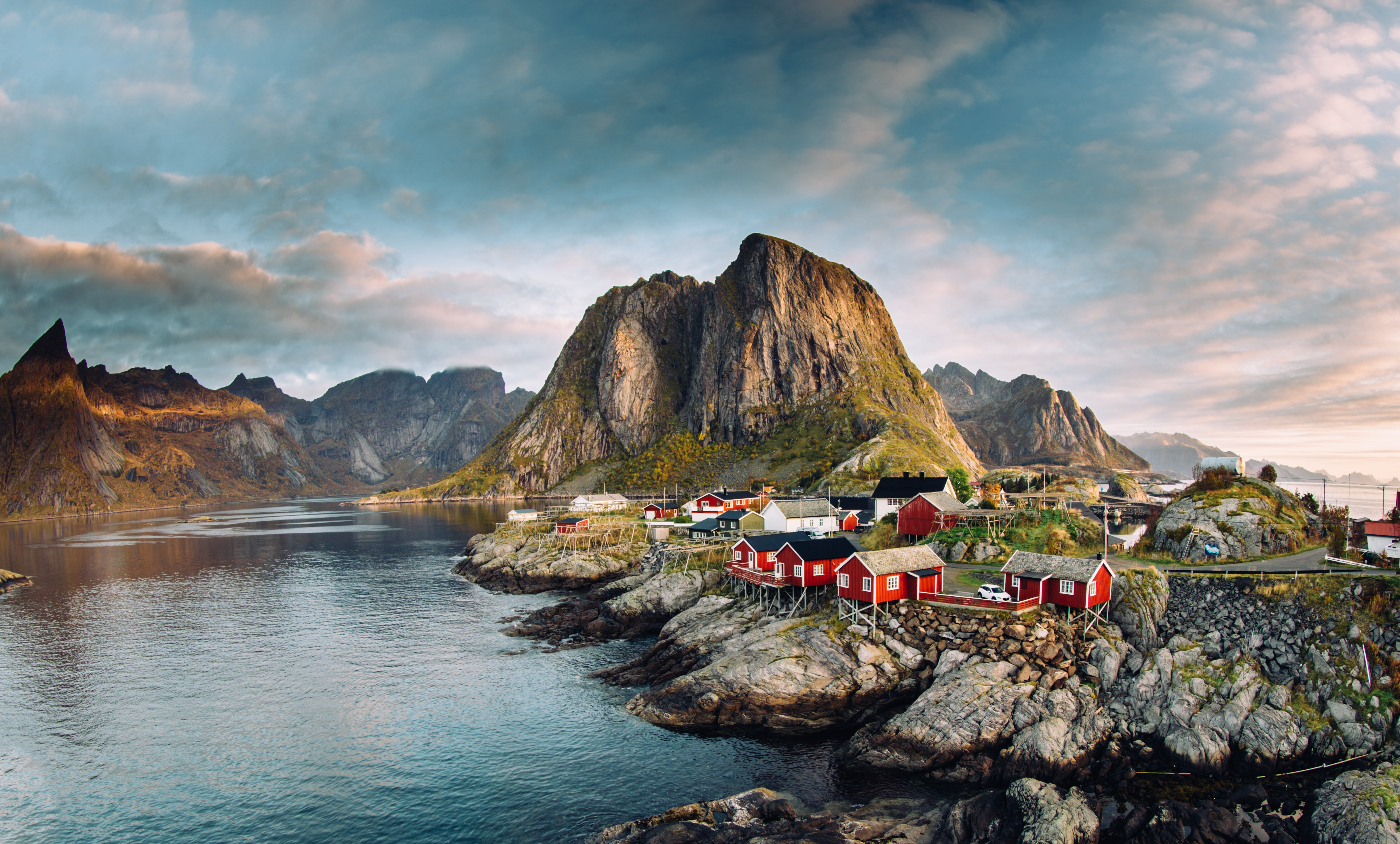 Stemningsfuld udsigt over den autentiske fiskerlandsby i Reine, Lofoten, med karakteristiske rode huse omgivet af majestætiske fjelde og fjord