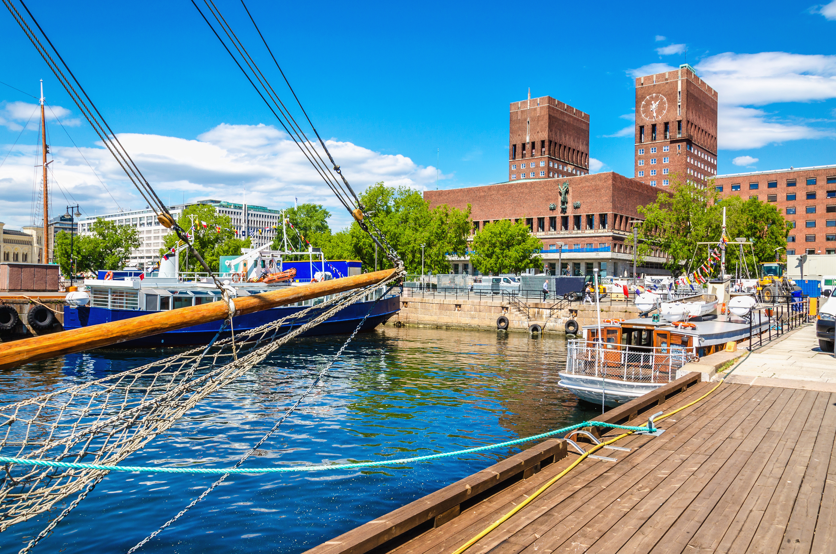 Historiske bygninger ved Oslo havn med sejlskibe og træbro