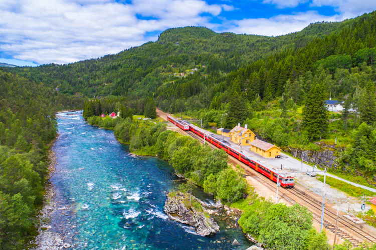 Malerisk norsk togrejse gennem bjerglandskab med turkisblå flod og tæt skov