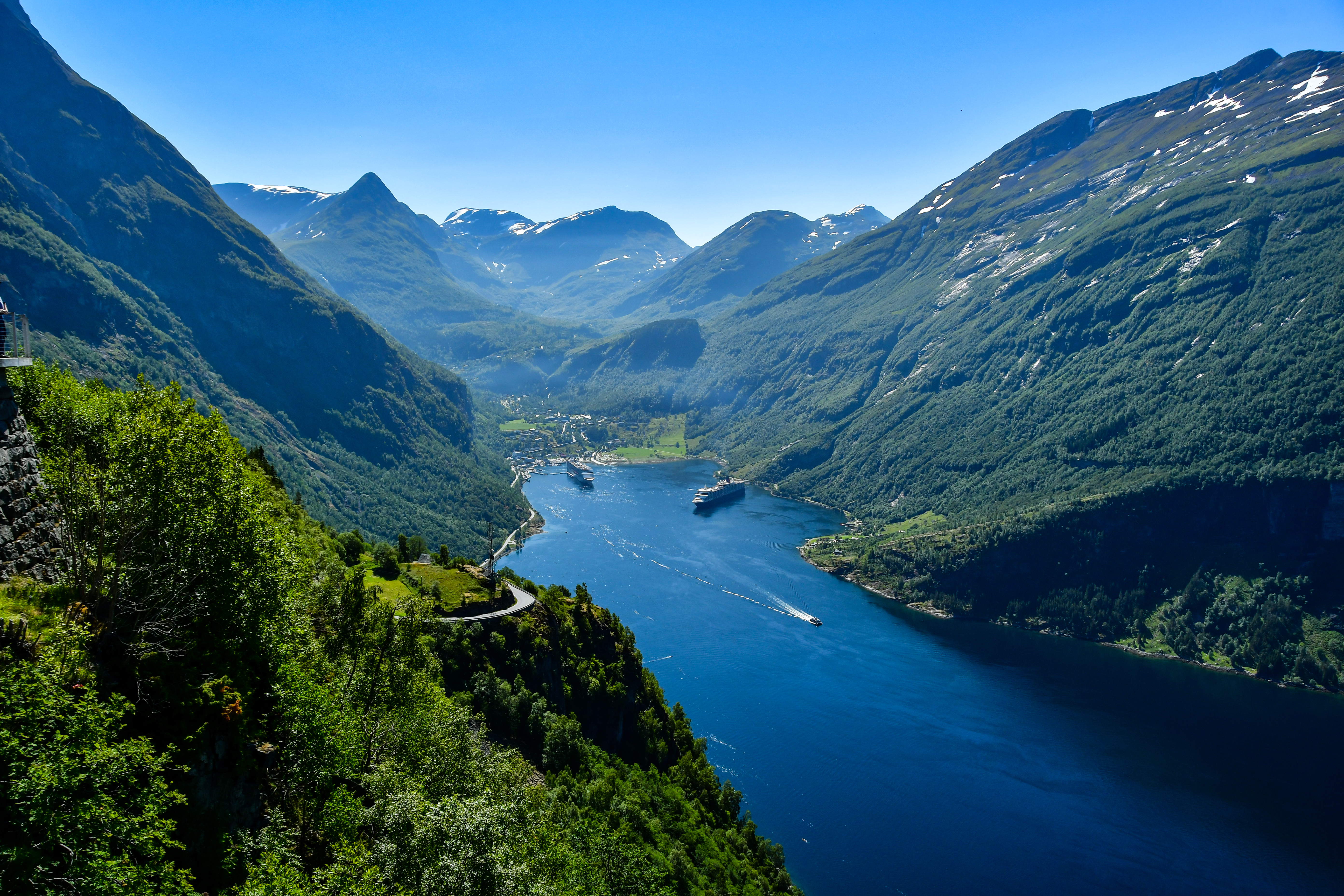 Magtfuld udsigt over den verdensberømte Geirangerfjord med krydstogtskibe navigerende gennem de dramatiske norske fjorde