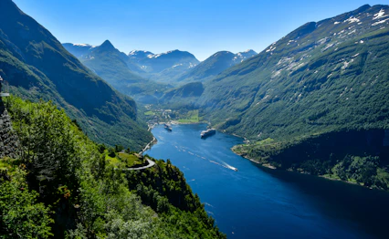 Magtfuld udsigt over den verdensberømte Geirangerfjord med krydstogtskibe navigerende gennem de dramatiske norske fjorde