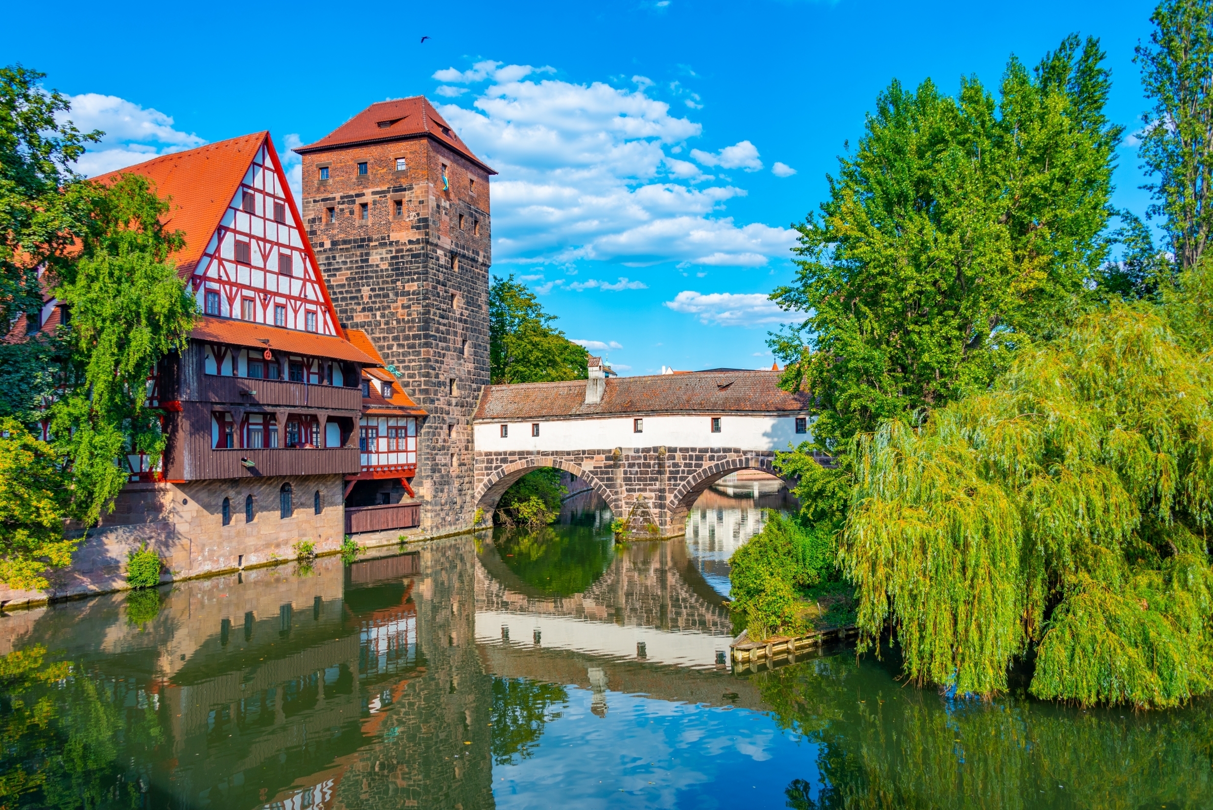 Idyllisk udsigt over det middelalderlige Nürnberg med Weinstadel-bygningen og Henkerbrücke-broen spejlet i den rolige Pegnitz-flod