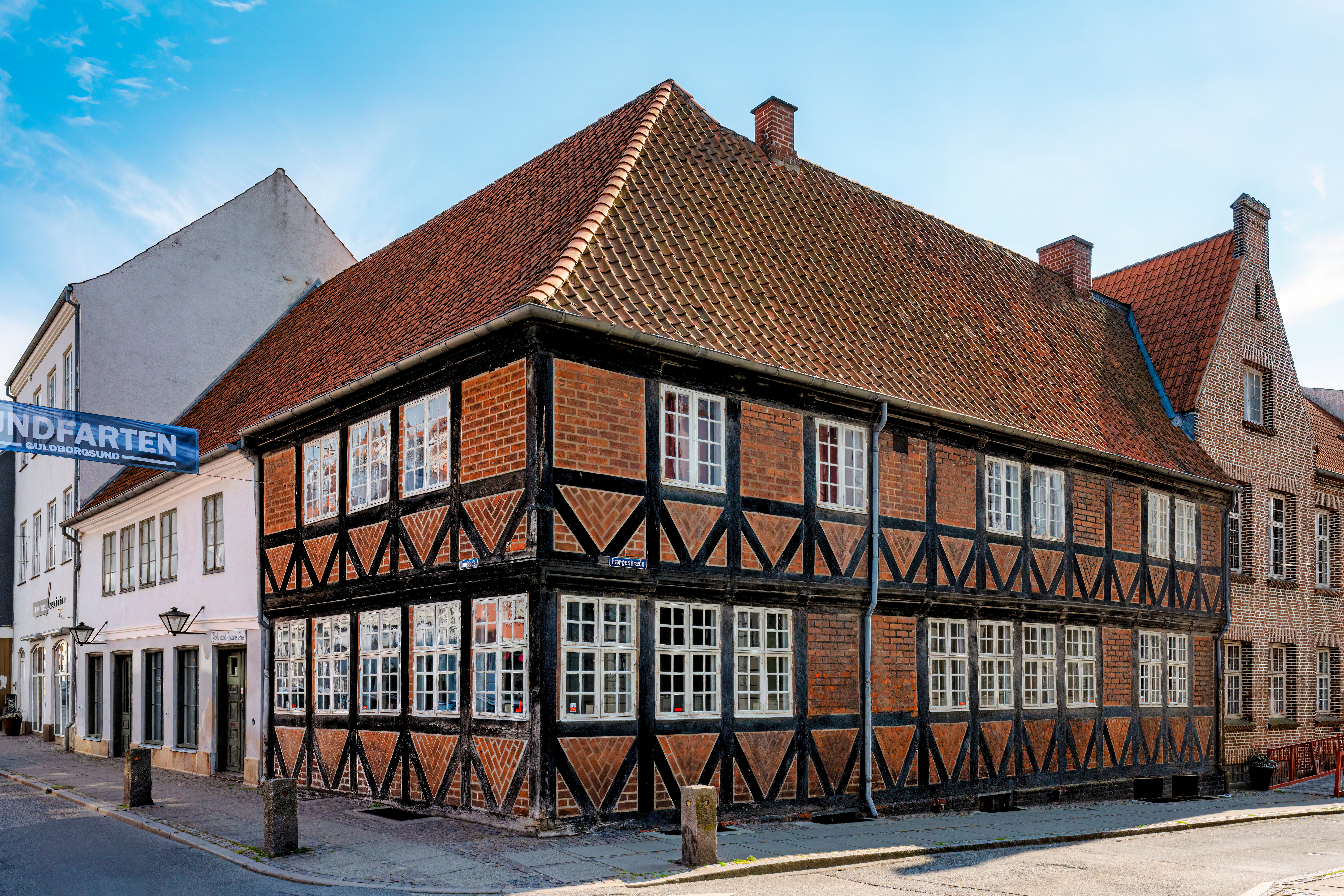 Gammelt bindingsværkshus på hjørnet af en brolagt gade i Nykøbing Falster med flot historisk dansk arkitektur