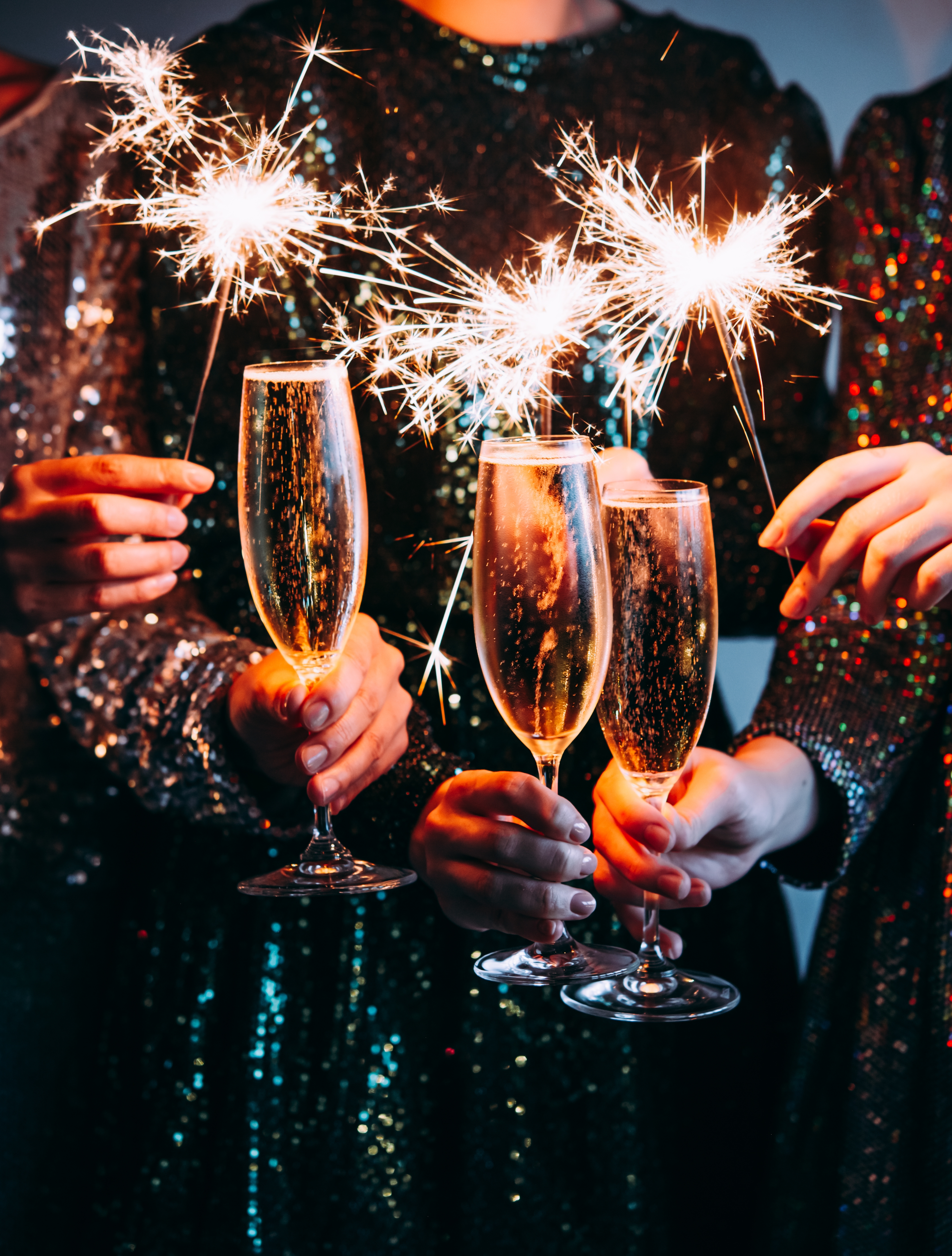 Glade venner skåler med mousserende vin og stjernekastere nytårsaften