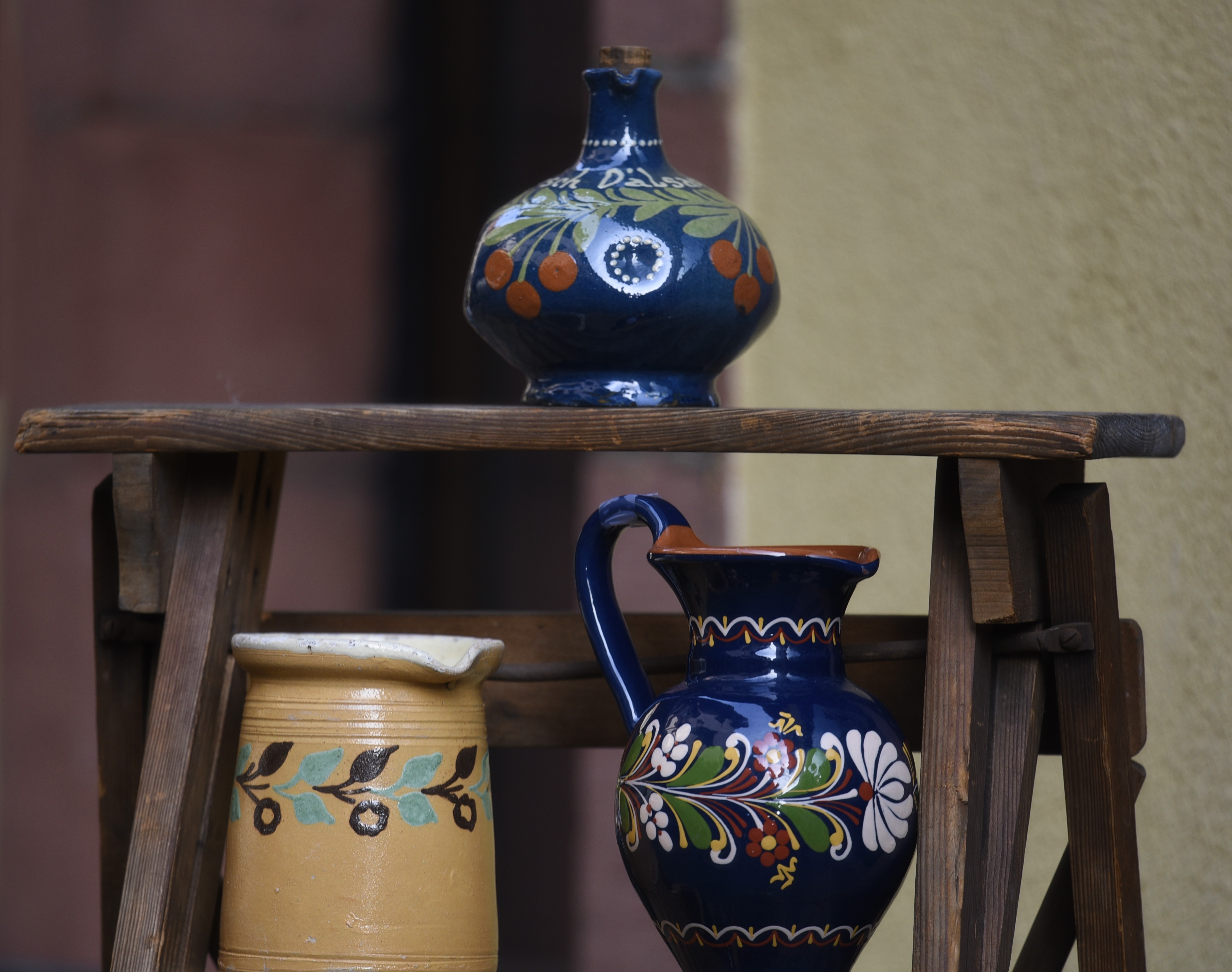 Vintage alsaciske keramikkander med håndmalede blomster og frugter på rustikt træstativ i Obernai, Alsace