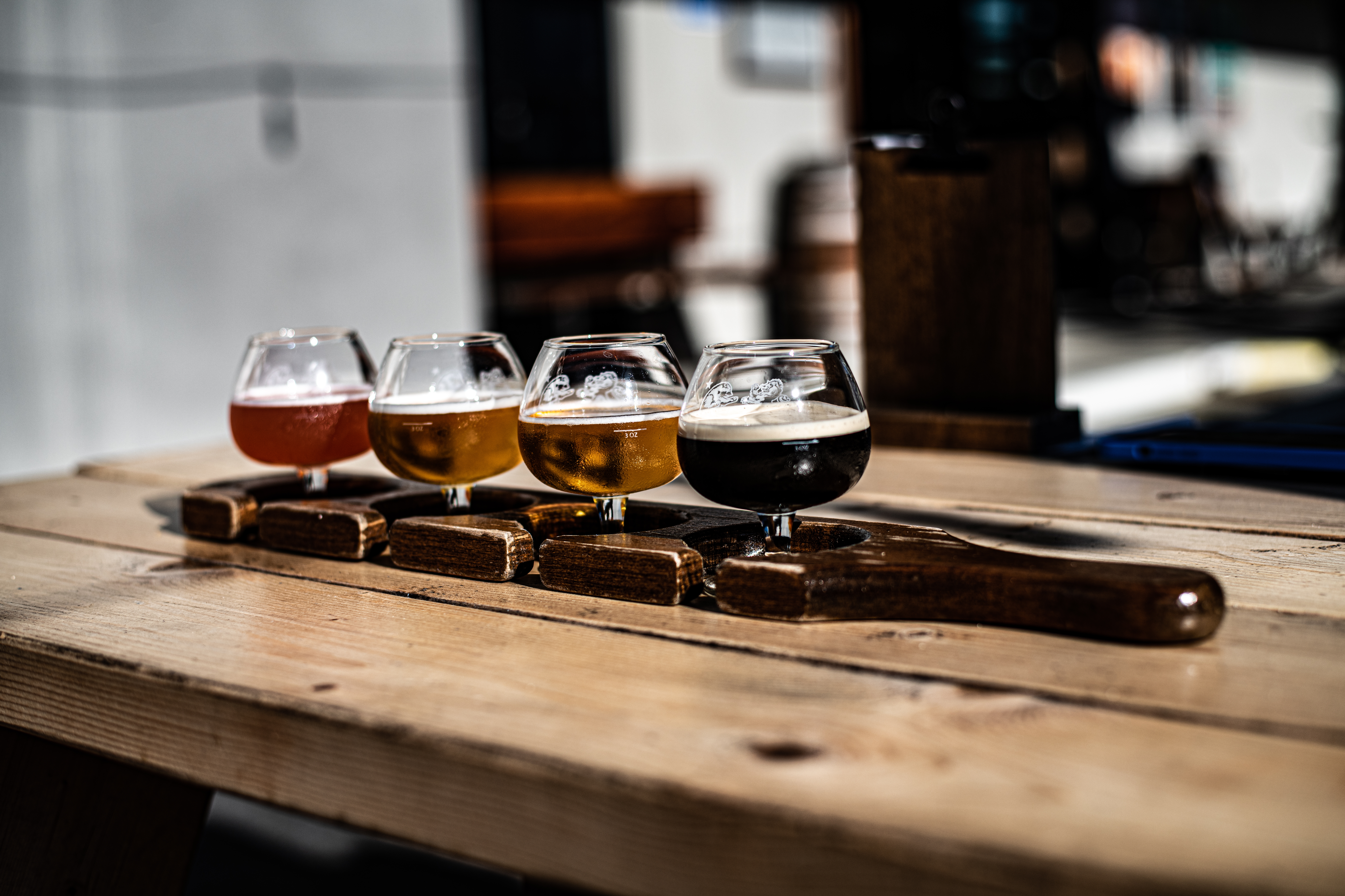 Lokal ølsmagning med fire forskellige craft beers fra lys til mørk på et rustikt træbord i et hyggeligt bryggeri