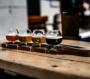 Lokal ølsmagning med fire forskellige craft beers fra lys til mørk på et rustikt træbord i et hyggeligt bryggeri