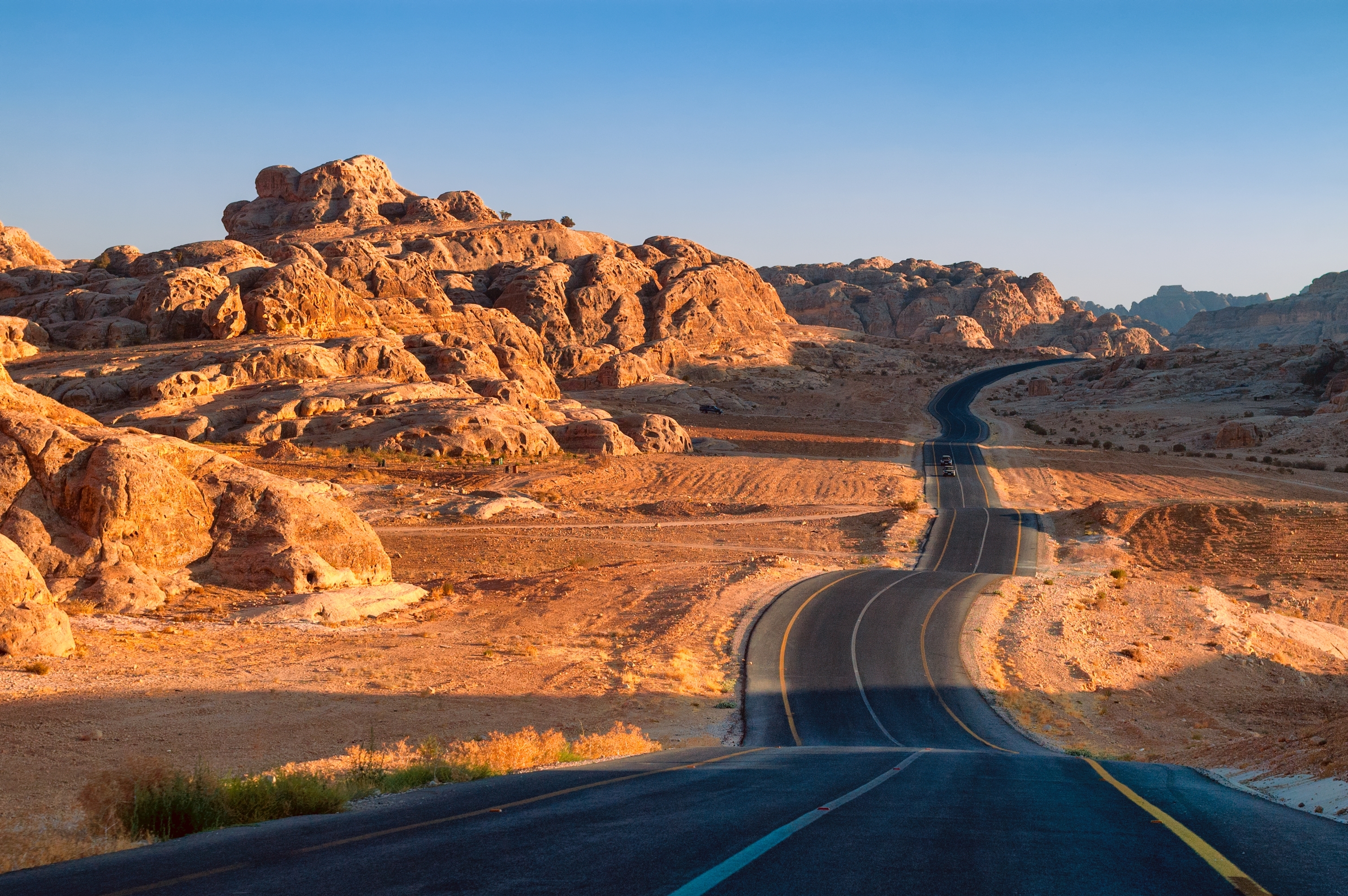Asfalteret vej der bugter sig gennem det spektakulære ørkenlandskab i Wadi Rum, Jordan med gyldne sandklitter og fjerne bjerge
