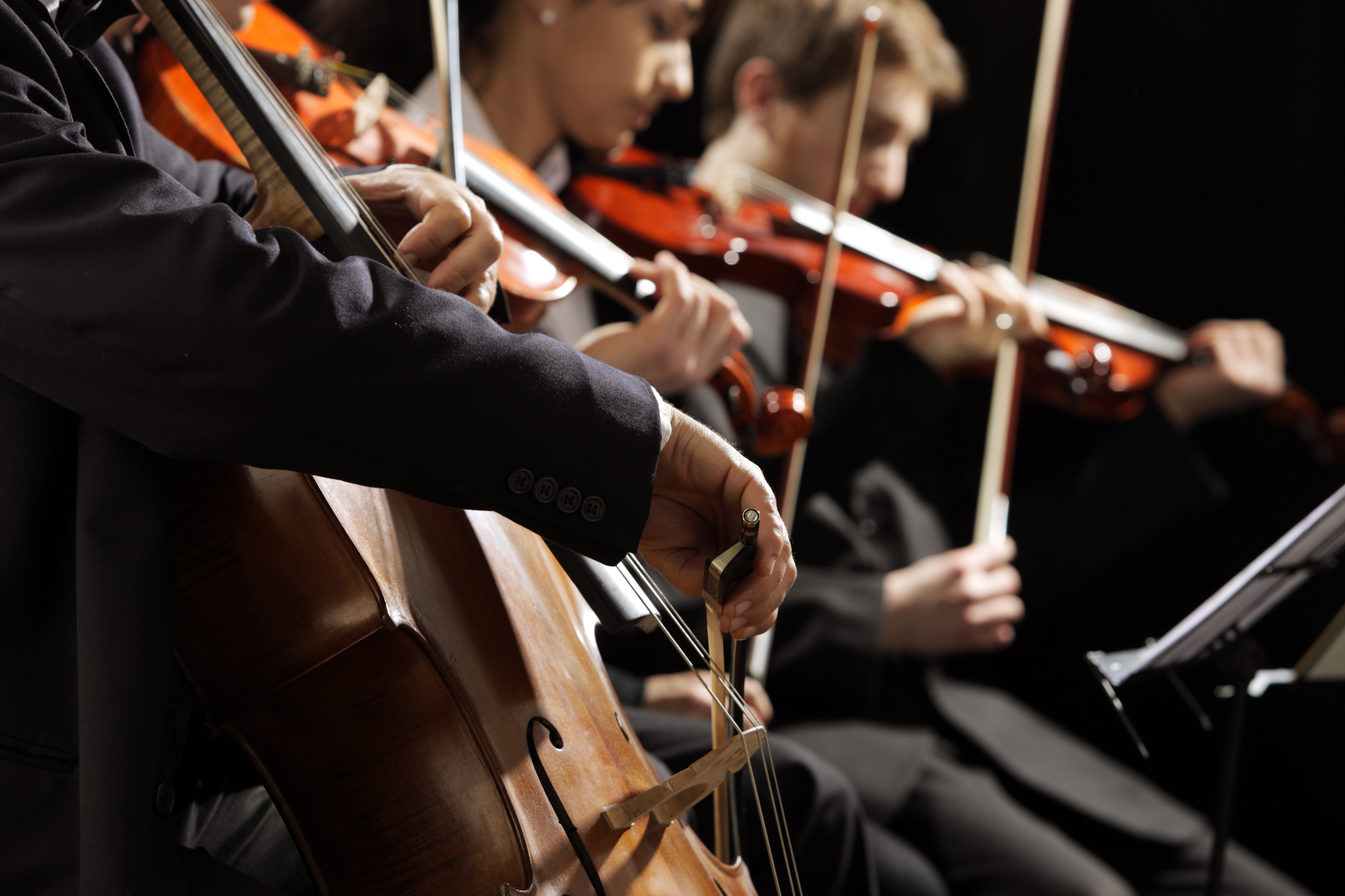 Klassisk orkesterkoncert med violinister og cellist i sort koncertsal