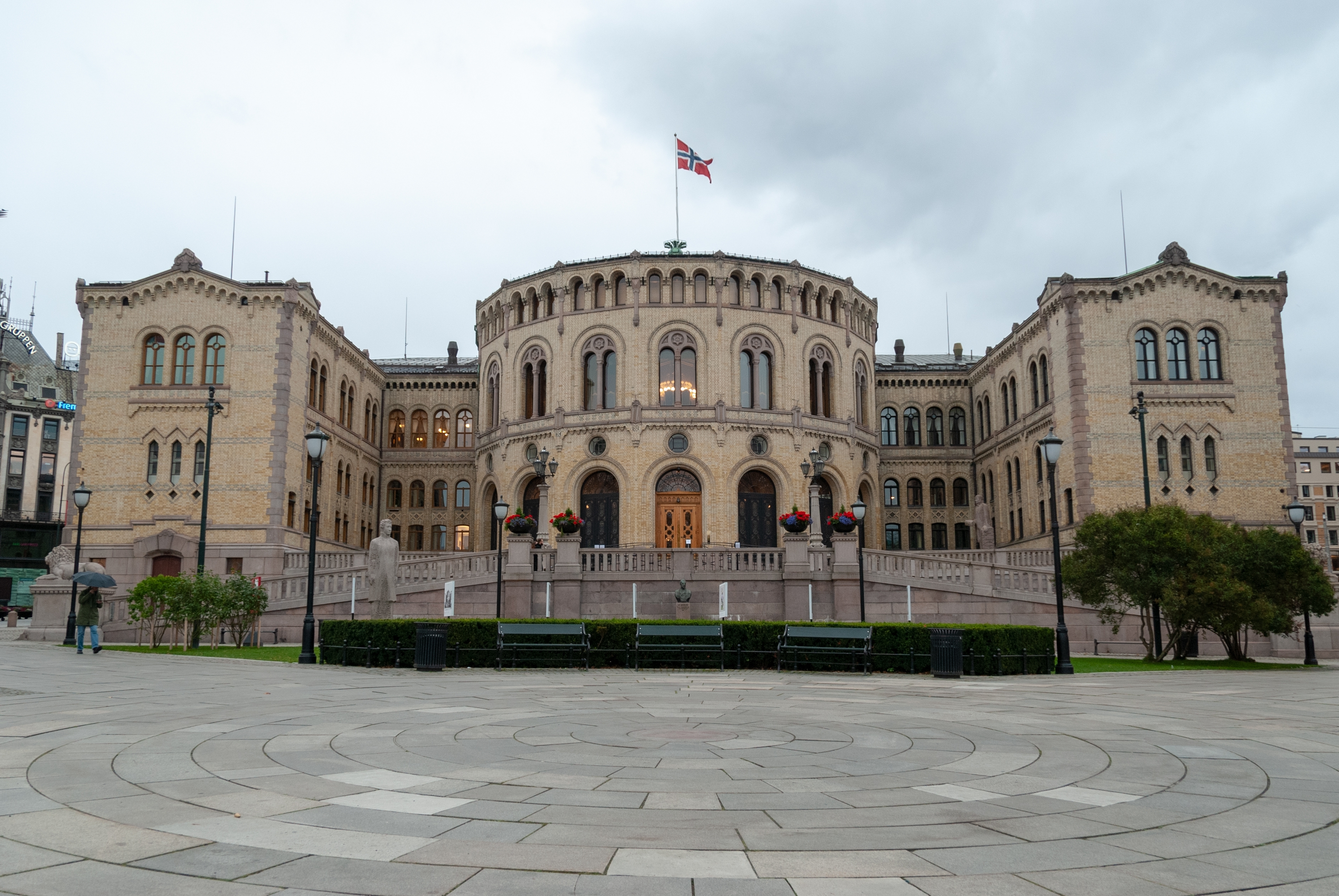 Stortinget i Oslo, Norges parlament, med majestætisk historisk facade og norsk flag ved Karl Johans gate i bycentrum