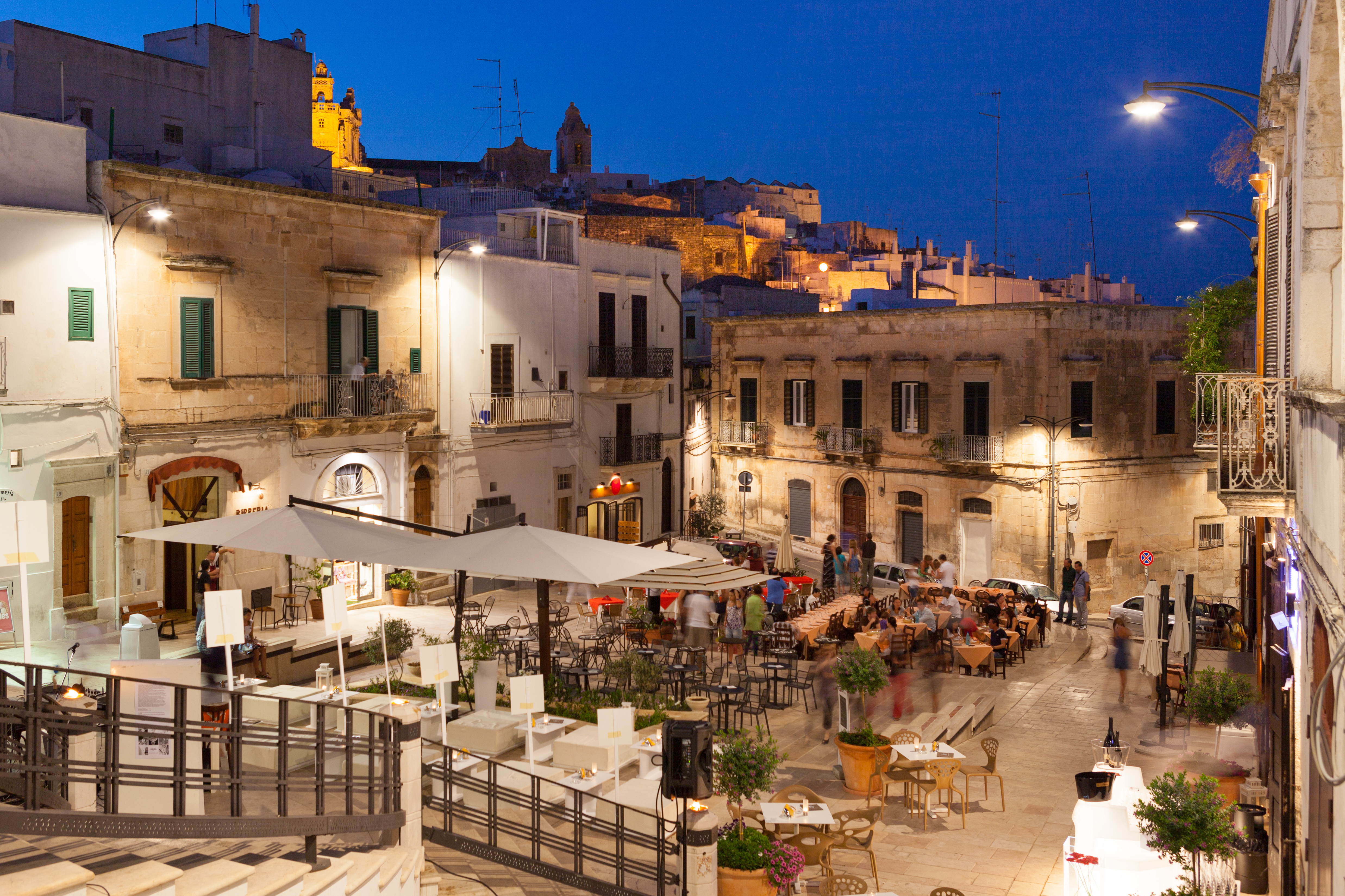 Livlig aftenstemning i Ostunis gamle bydel i Puglia med udendørs dining og pittoreske hvide bygninger i tusmørket
