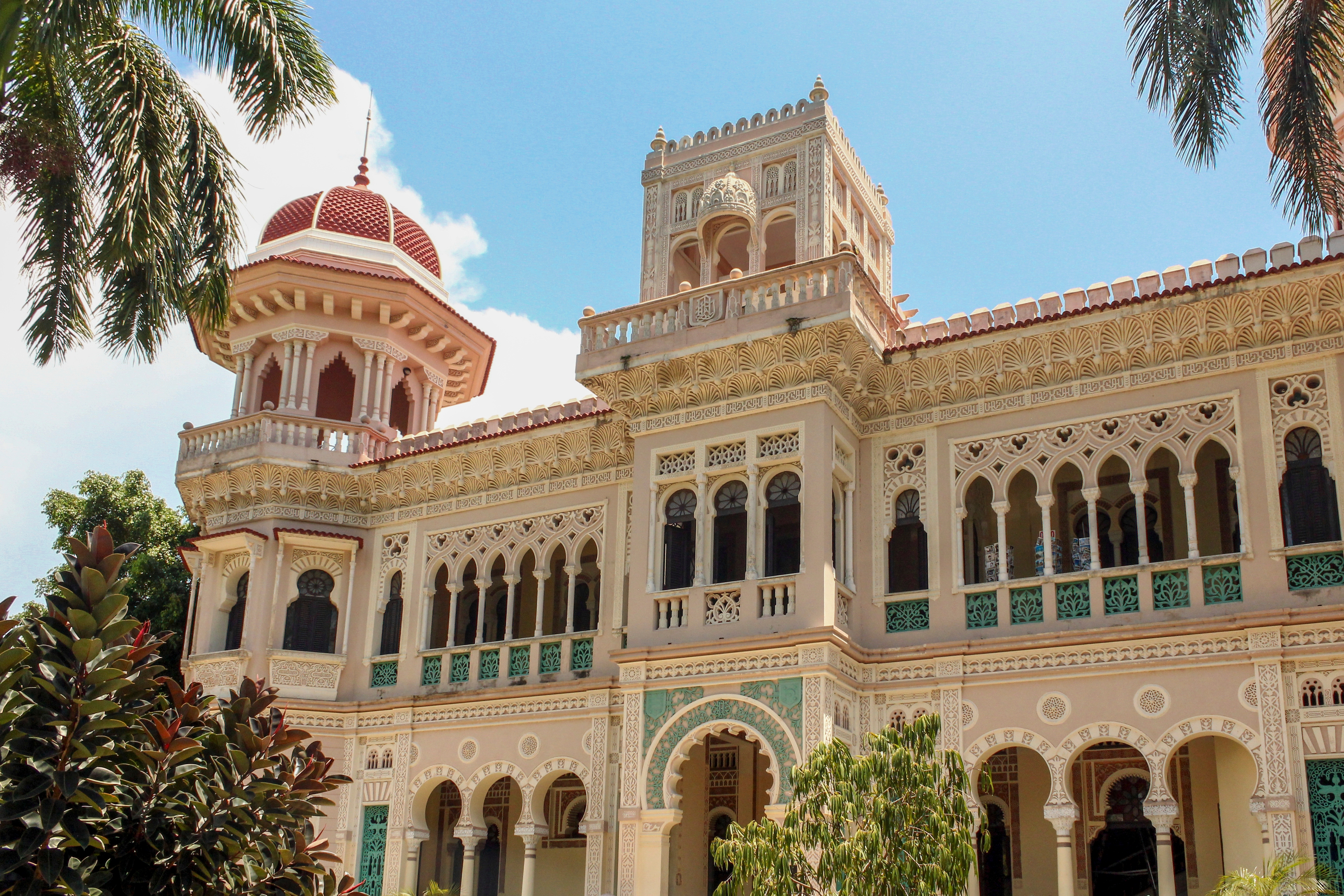 Palacio del Valle i Cienfuegos, Cuba - et pragtfuldt eksempel på maurisk kolonialarkitektur med ornamenterede buer, hvide balkoner og tropiske palmtræer