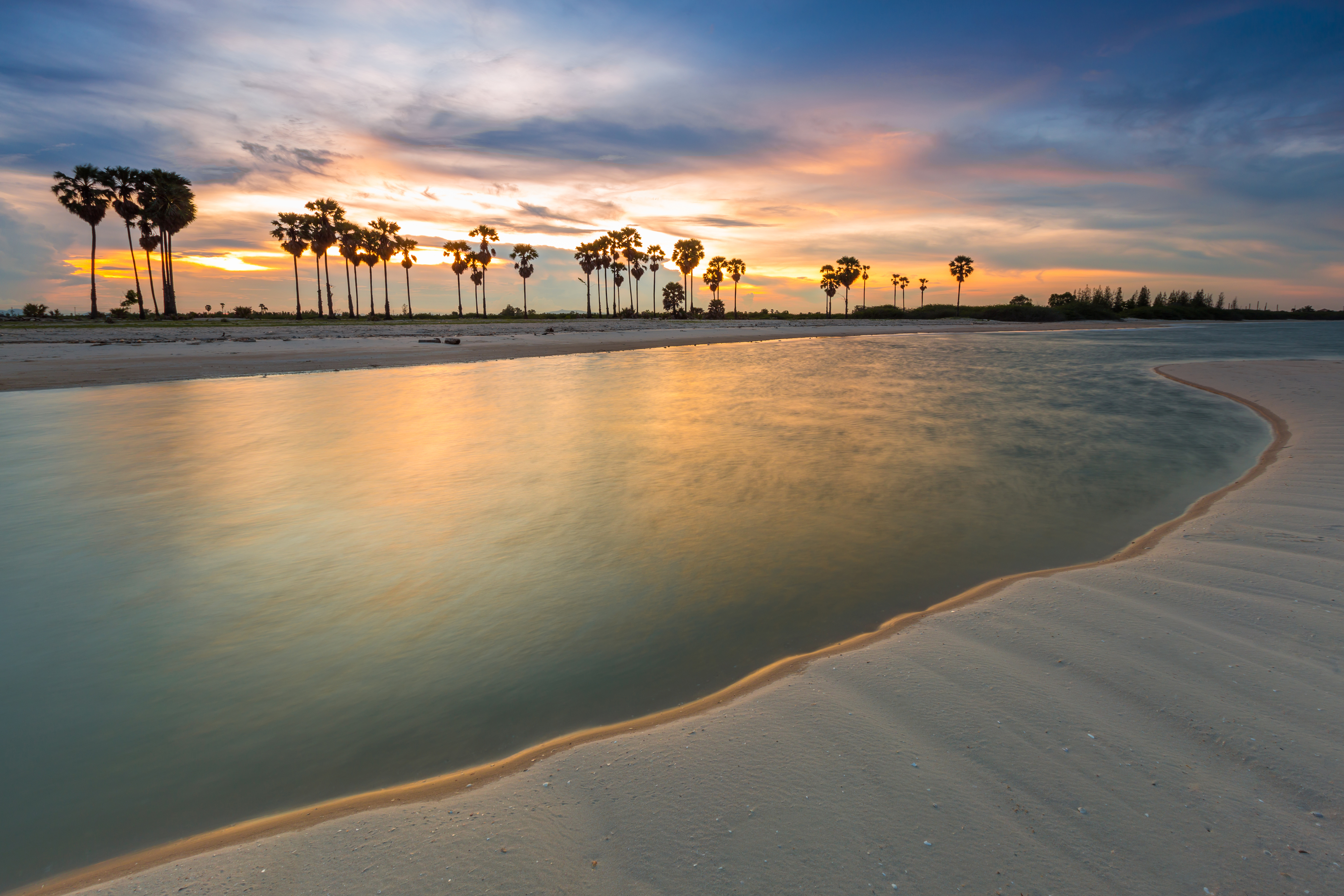 Malerisk palmer på hvid sandstrand med farverig solnedgang i Thailand