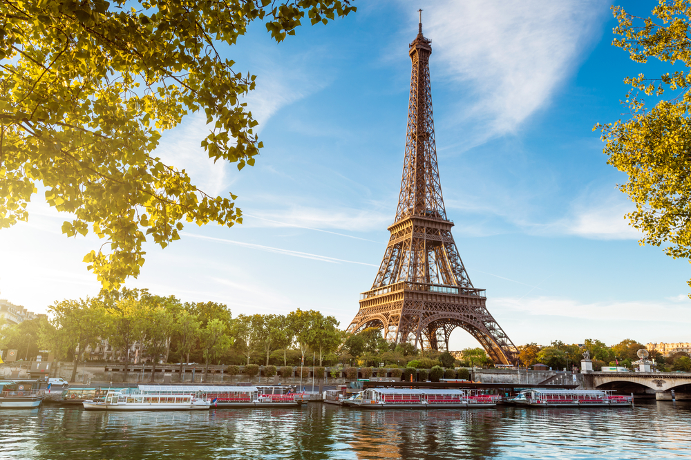 Paris rejse med Eiffeltårn Seine flod turistbåde i solskin