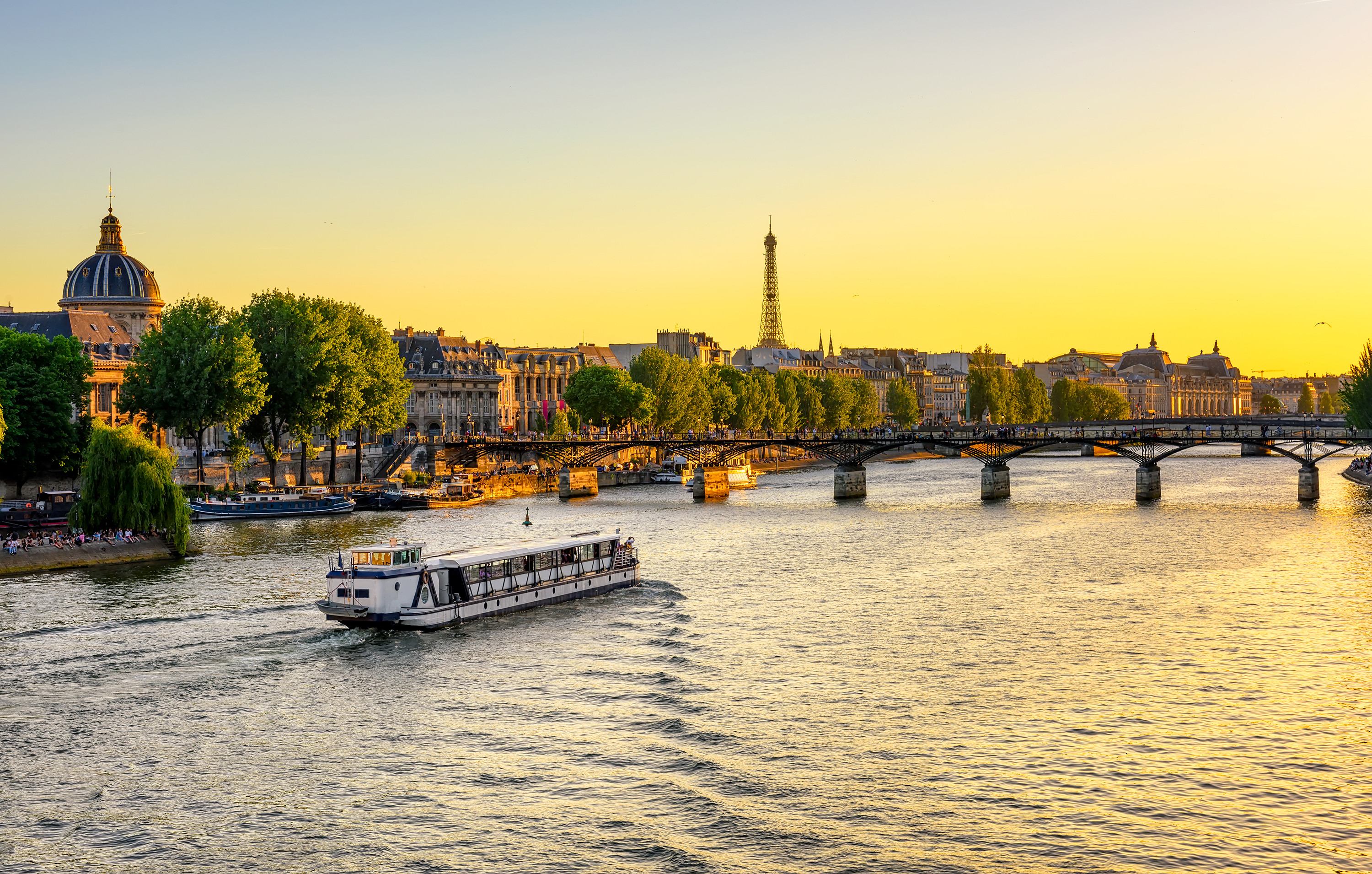 Turistbåd på Seine floden med Pont des Arts bro og Eiffeltårnet i baggrunden