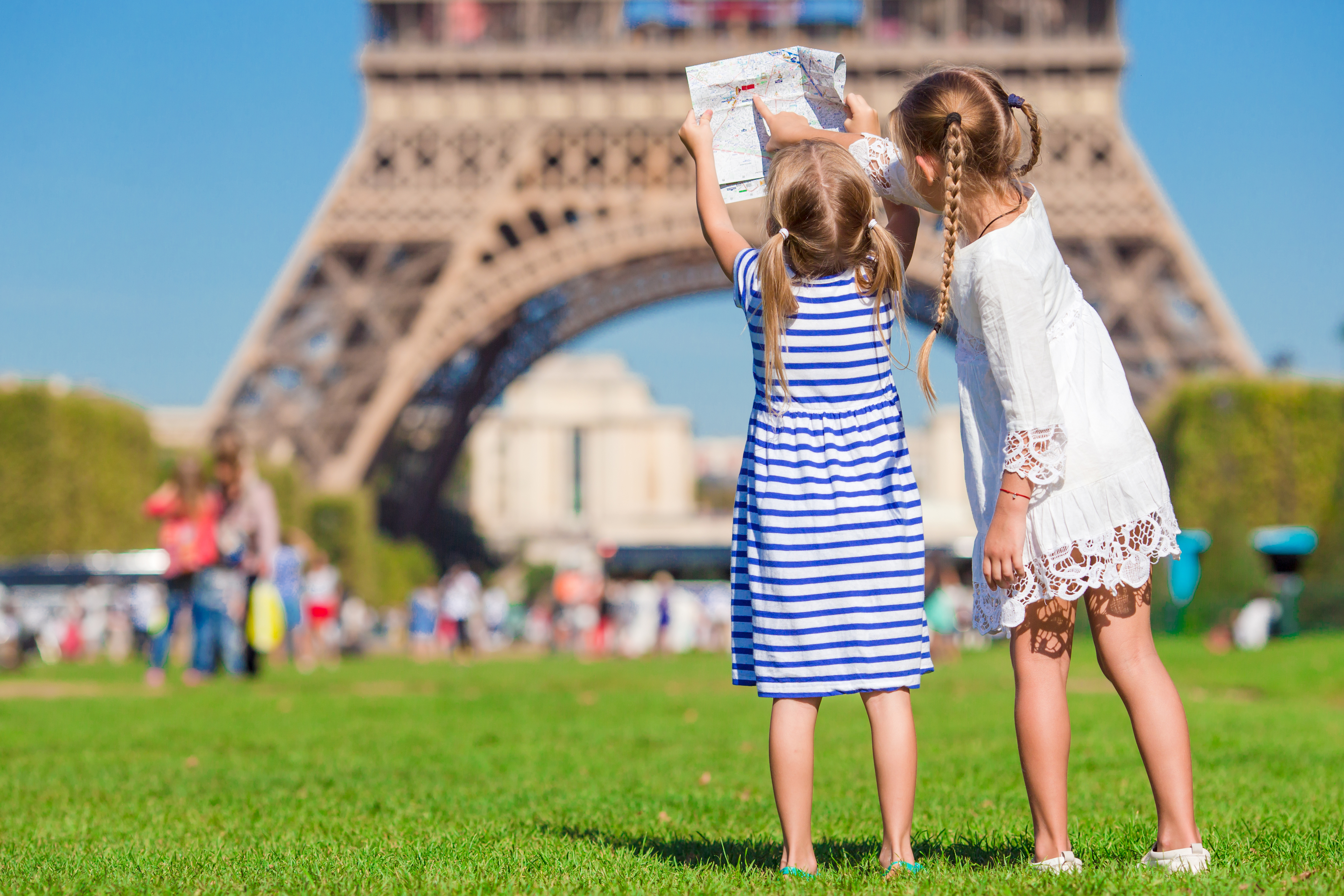 Søstre med turistkort foran det berømte Eiffeltårn i Paris