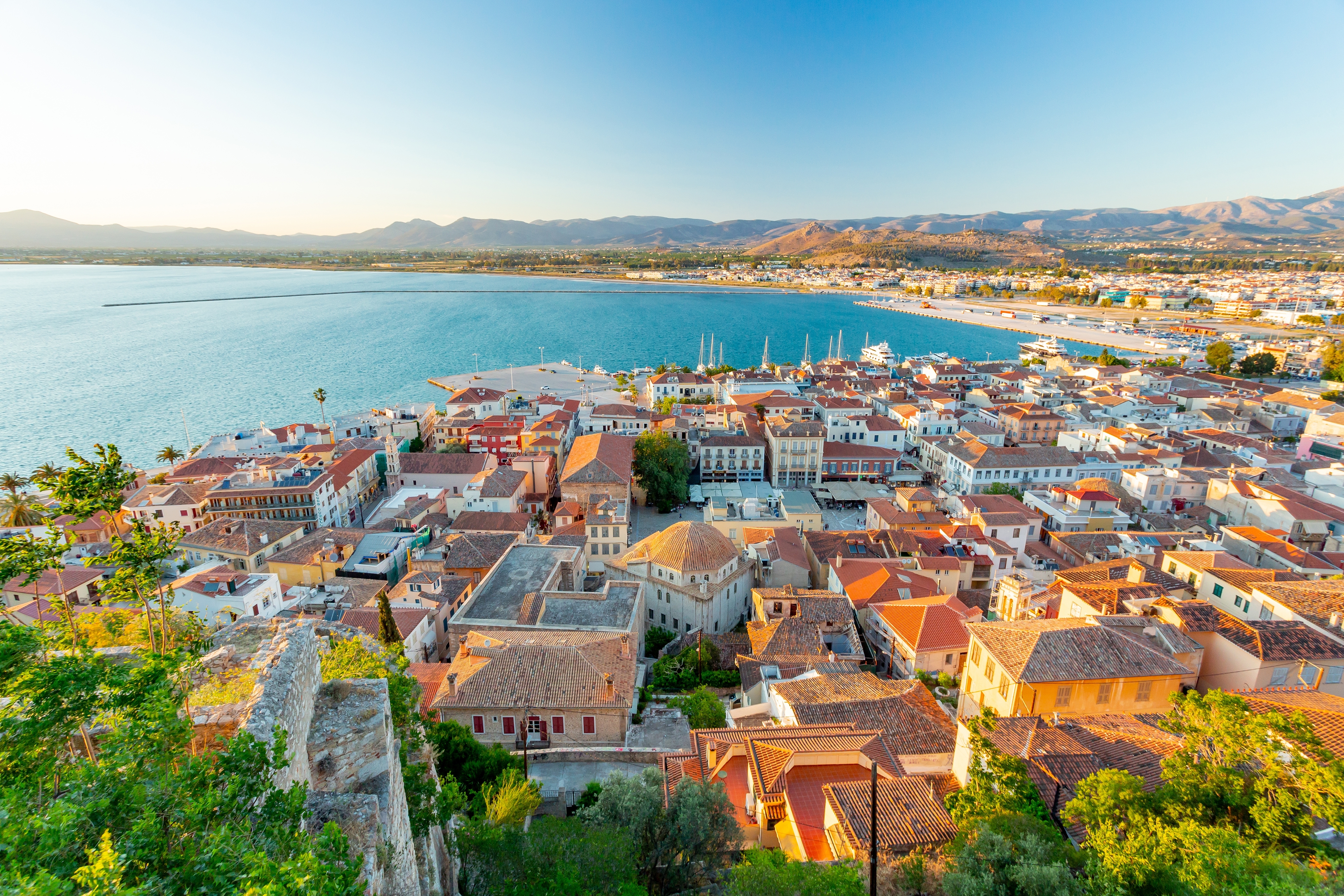 Fascinerende panoramabillede af den historiske by Nafplio med dens terrakottafarvede tage, den blå bugt med både og de omkringliggende bjerge på Peloponnes-halvøen