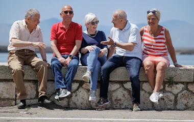 Pensionister på gruppeferie nyder solrig dag ved havnen