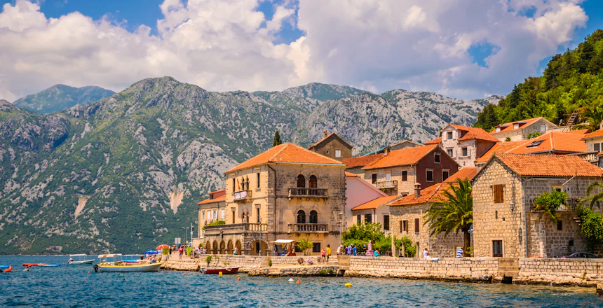 Traditionel stenarkitektur i Perast, Montenegro ved fjordlandskab med høje bjerge